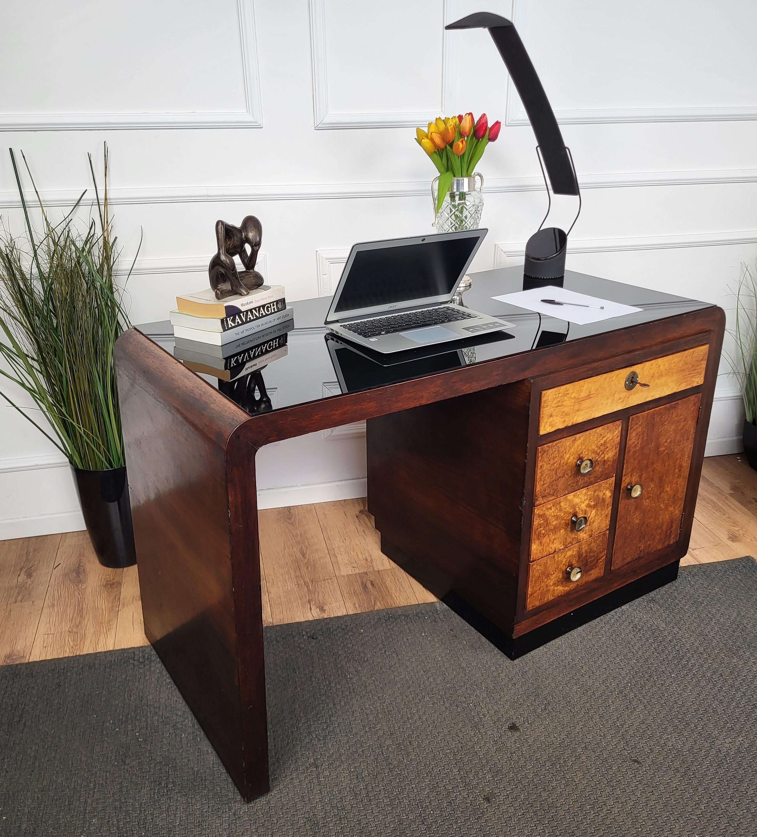 Beautiful Italian Art Deco Mid-Century Modern desk writing table, in veneer burl wood and precious black opaline glass top, with elegant carved frame and curved sides highlighted by the black details and completed by the side, back and front door