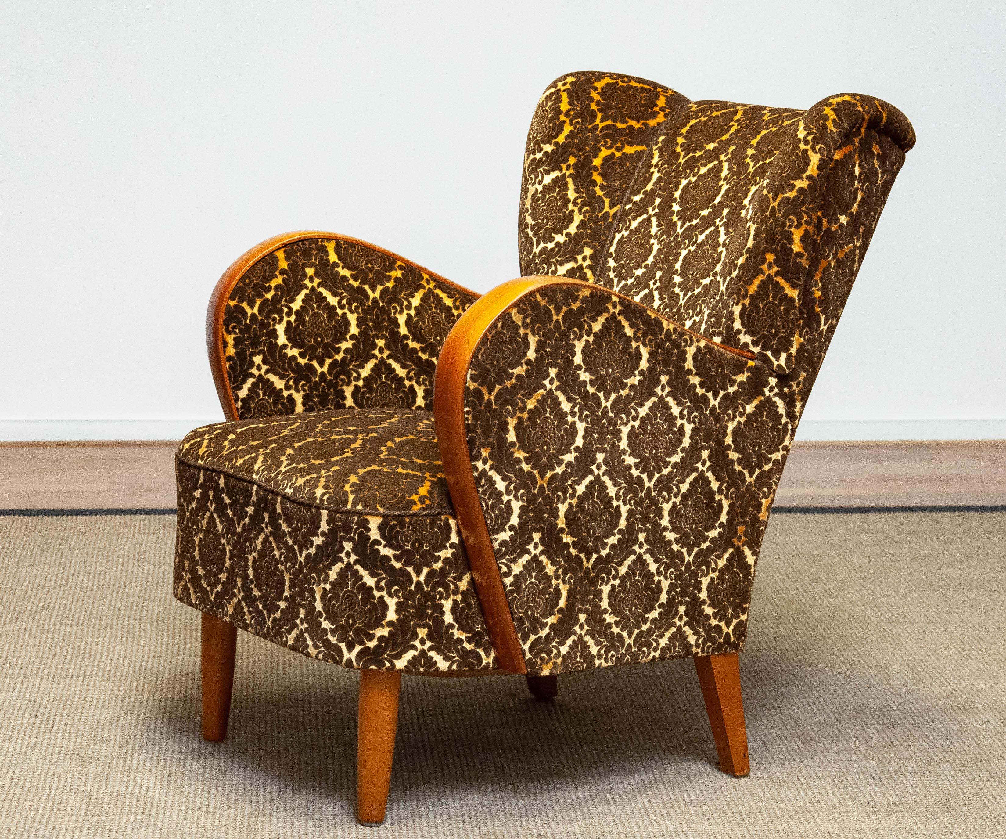 Absolutely beautiful and complete original Scandinavian lounge / club chair in the style of Fritz Hansen made in Danmark.
This lounge / club chair is upholstered with gold and brown mixed jacquard velvet fabric. The bentwood armrests are made of