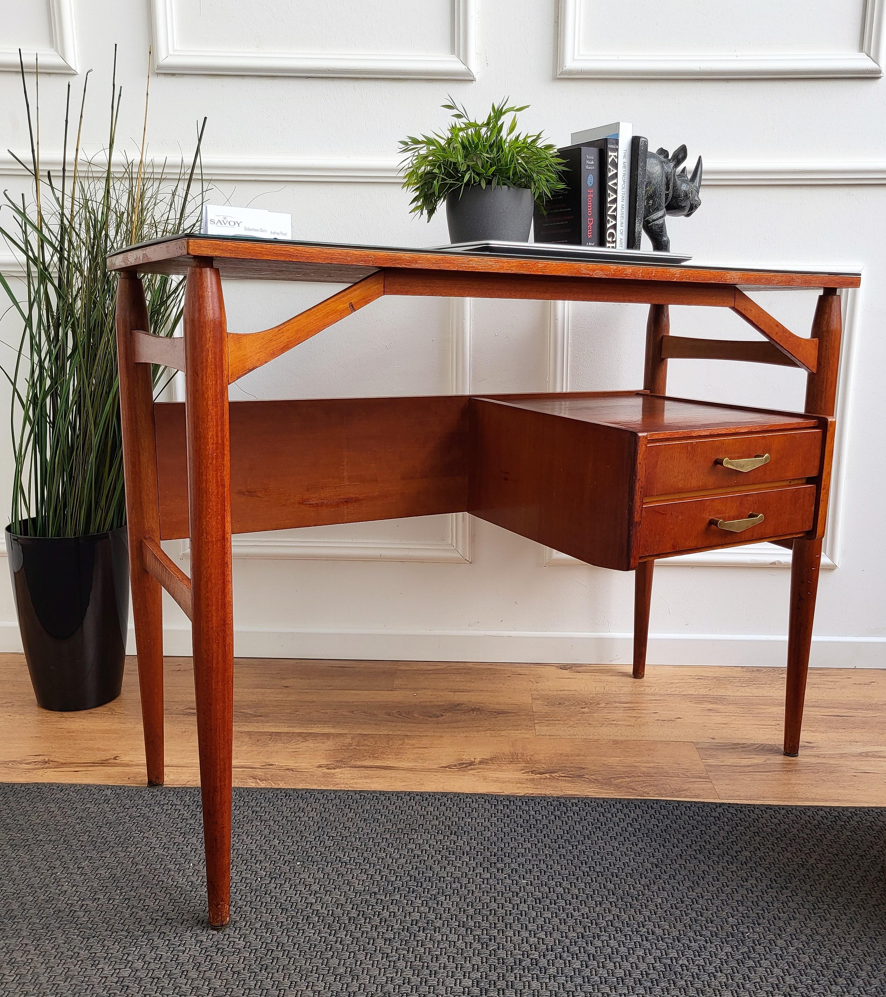 Very elegant Italian Art Deco Mid-Century Modern desk writing table, with black glass top and beautiful 4 side carved legs and junctions with two floating side drawers drawers completed with great brass handles. The unique and typical design, with