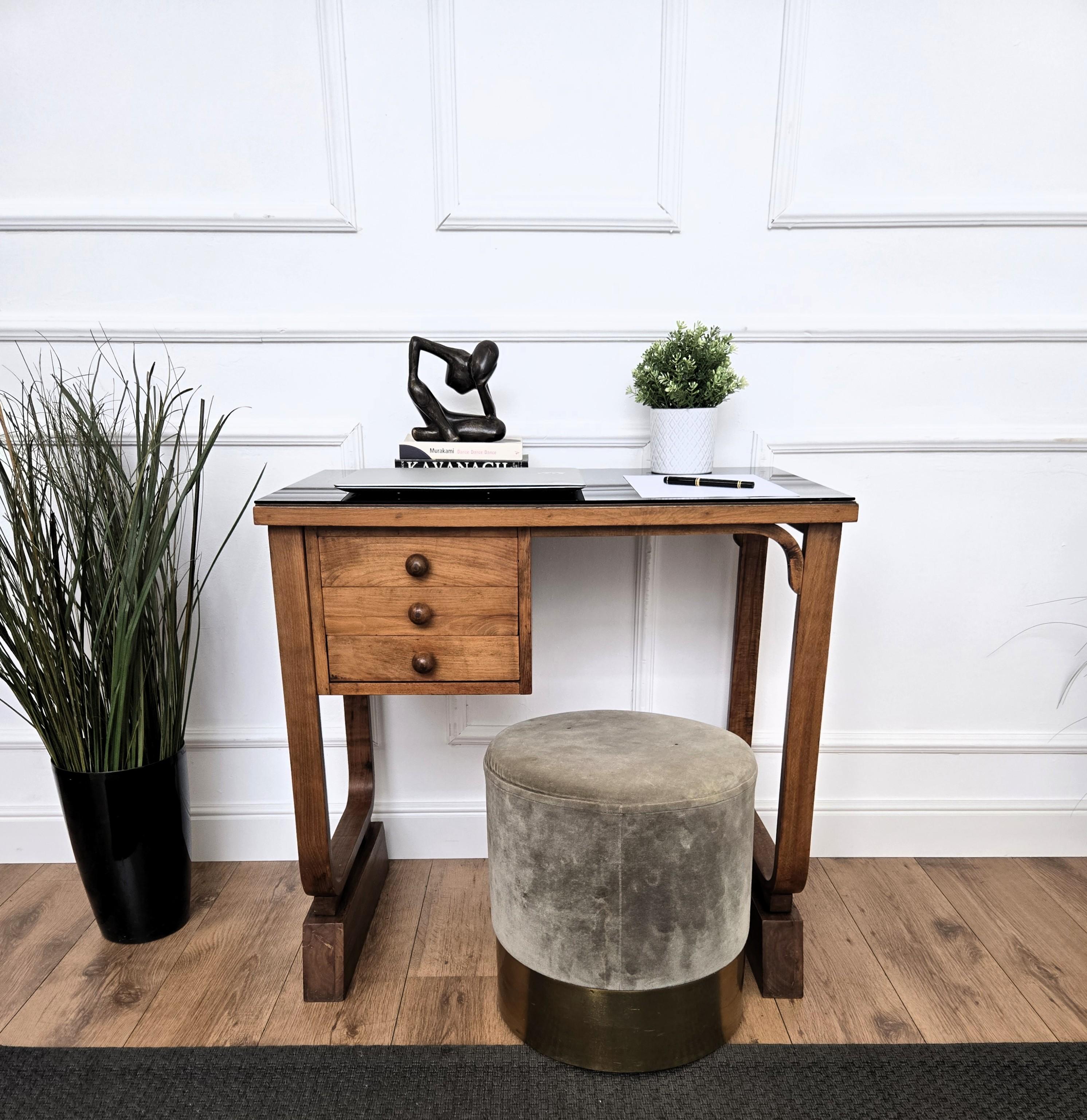 Magnifique table à écrire Art déco italien du milieu du siècle, en bois de ronce plaqué, avec plateau en verre noir, élégants côtés incurvés complétés par trois tiroirs latéraux. Le design unique et typique, avec ses formes géométriques nettes,