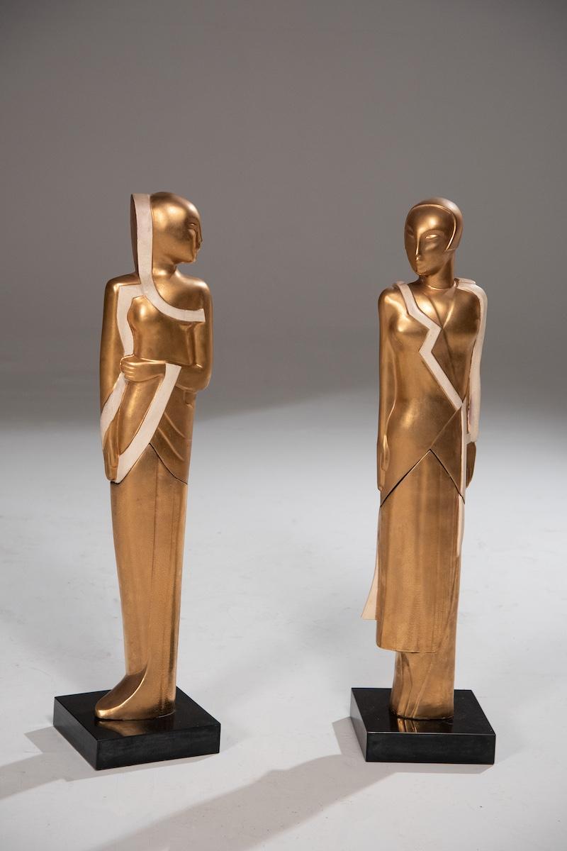 Elegante coppia di sculture Art Deco risalenti agli anni '30, realizzate nello stile di Gustave Miklos. I pezzi raffigurano due figure in piedi, scolpite con grande raffinatezza e attenzione ai dettagli.

Realizzati in ceramica craquelé dorata e in
