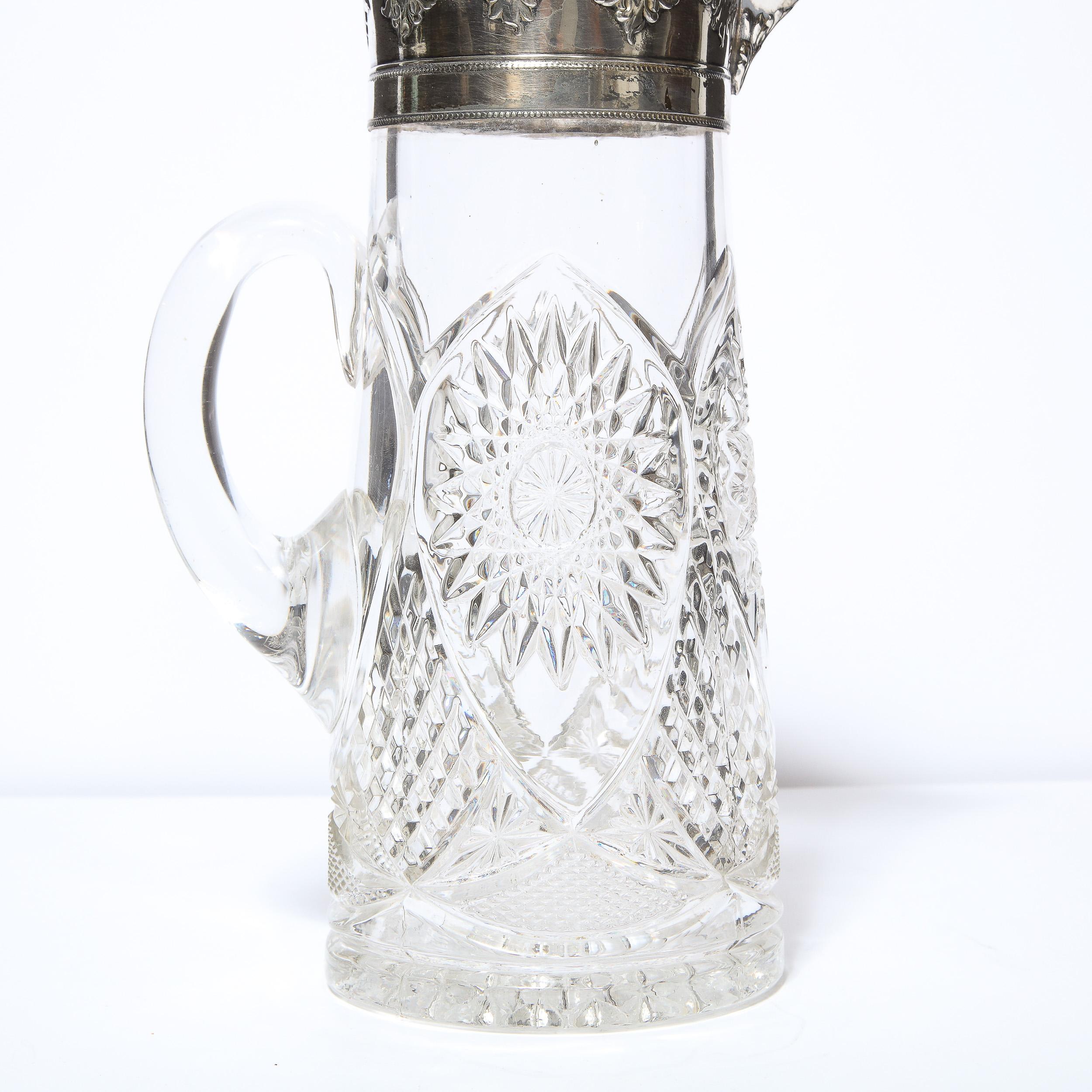 This elegant 1940s Art Deco pitcher was realized in the United States circa 1940. It features a slightly tapered cylindrical body with a streamlined handle and silver plated top. There are geometric designs including arches, diamond and sunburst