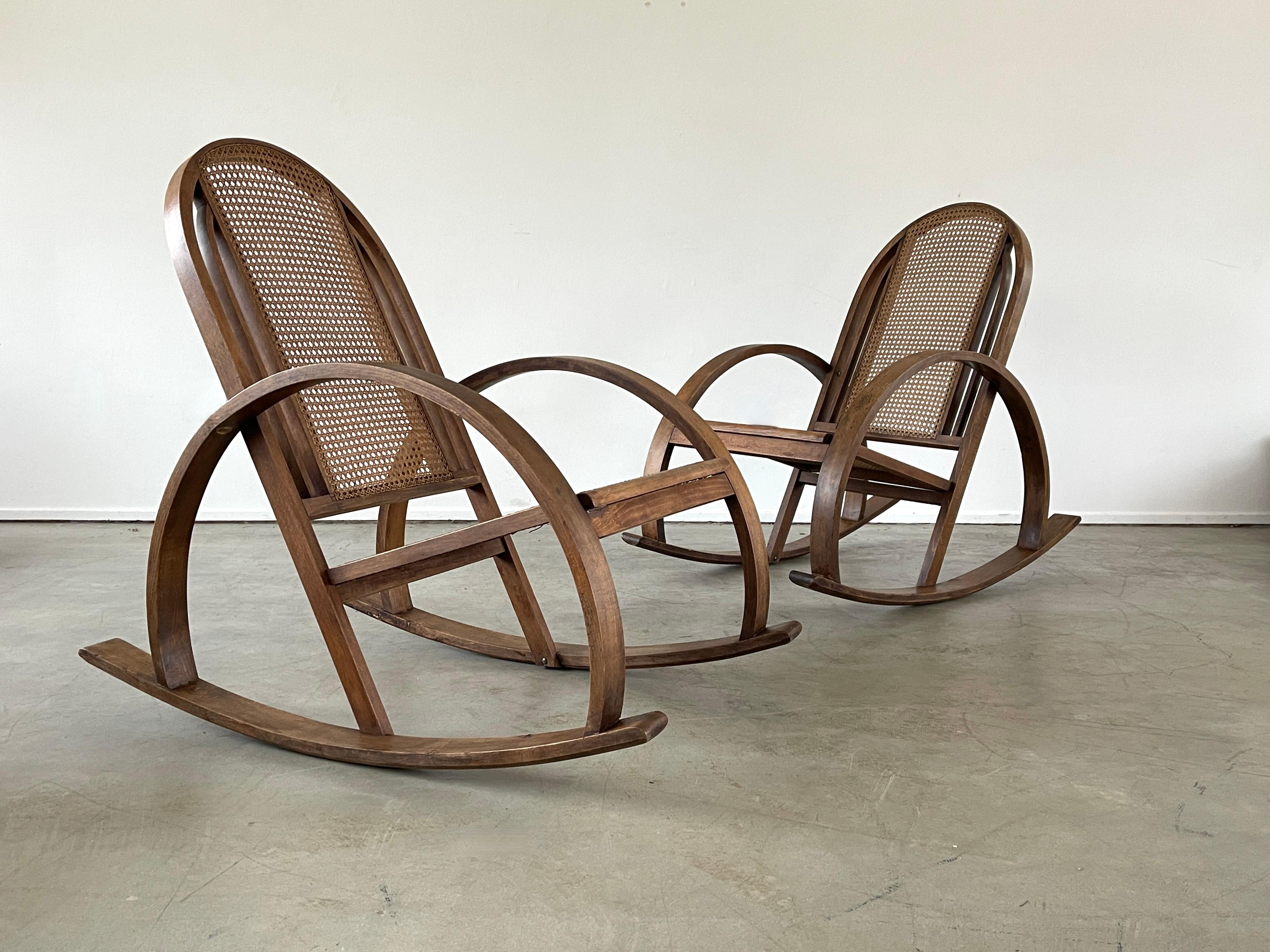 Beautiful pair of Art Deco caned rocking chair with unique shape and great style. 
Caned seat and back with curved oak frame with patina'd wood.