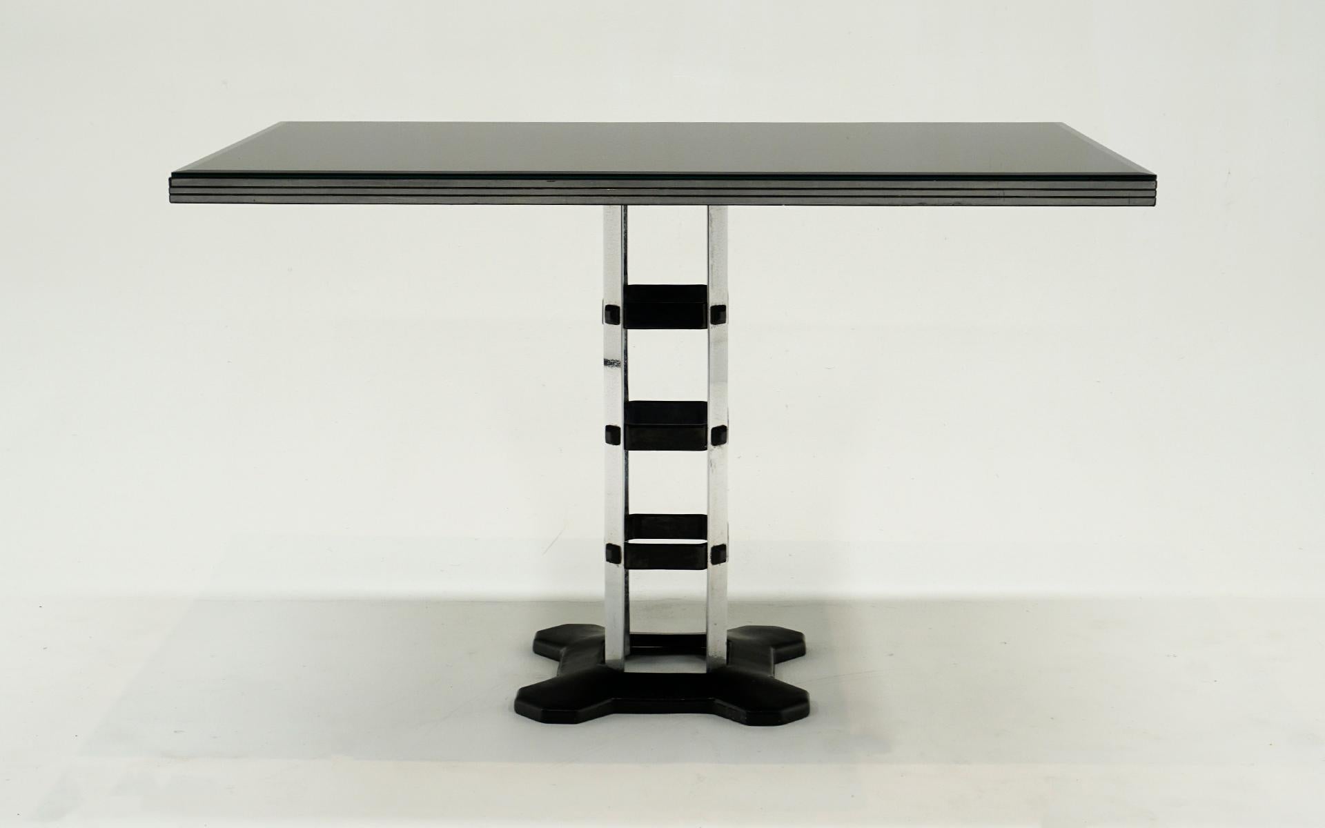Table de salle à manger Art déco/machine des années 1940. Lourde base en fonte et structure de support chromée. La table est composée d'un plateau en bois noir plat et d'un verre peint en noir inversé. Les rayures sur le verre que nous montrons dans