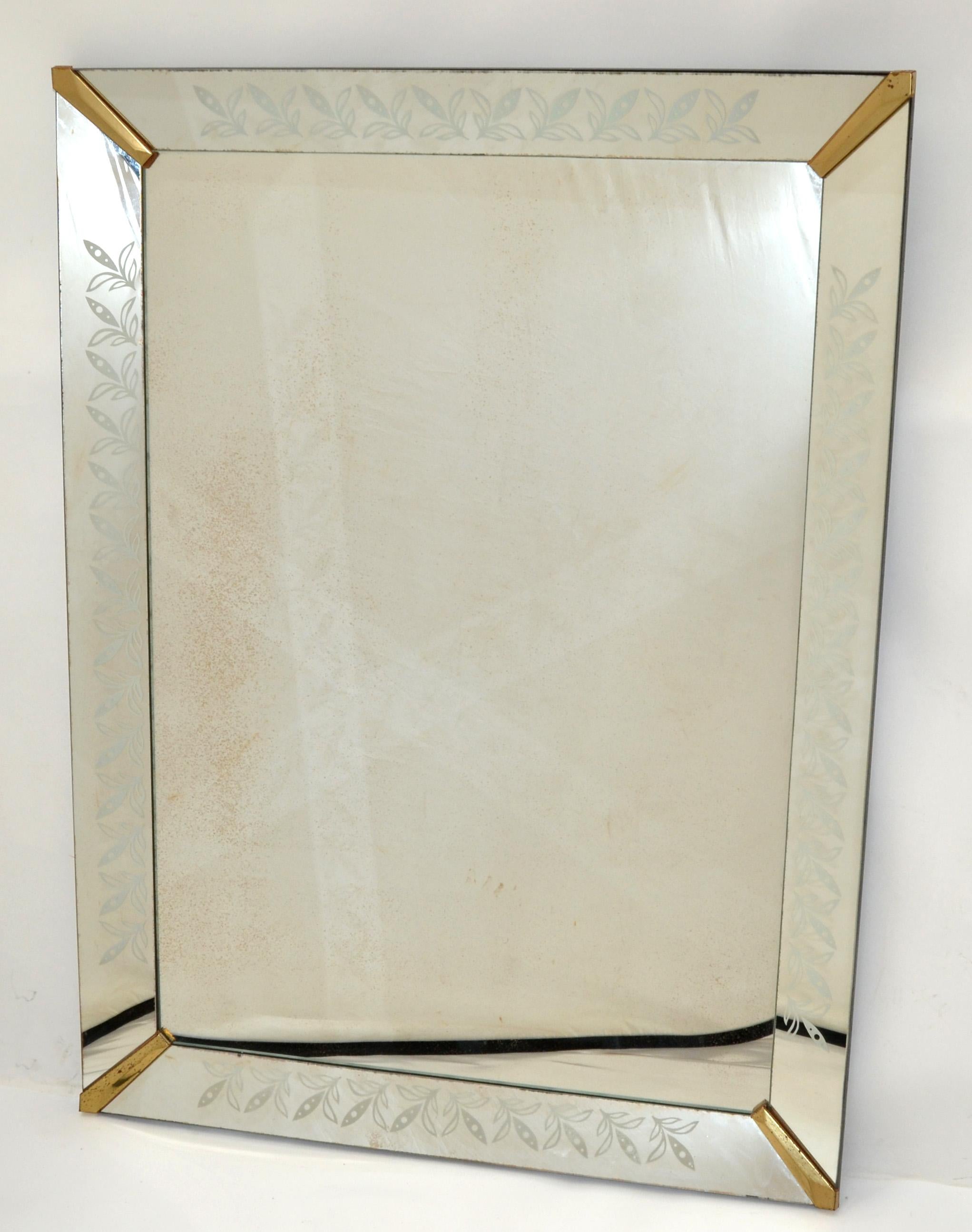 Decorative 1940s Venetian style mirror with beveled glass frame and brass finished metal corners. 
The wave Glass panels are etched with a flower decor.
The mirror has a very heavy solid wood backing in black finish.
Can be hung vertically or