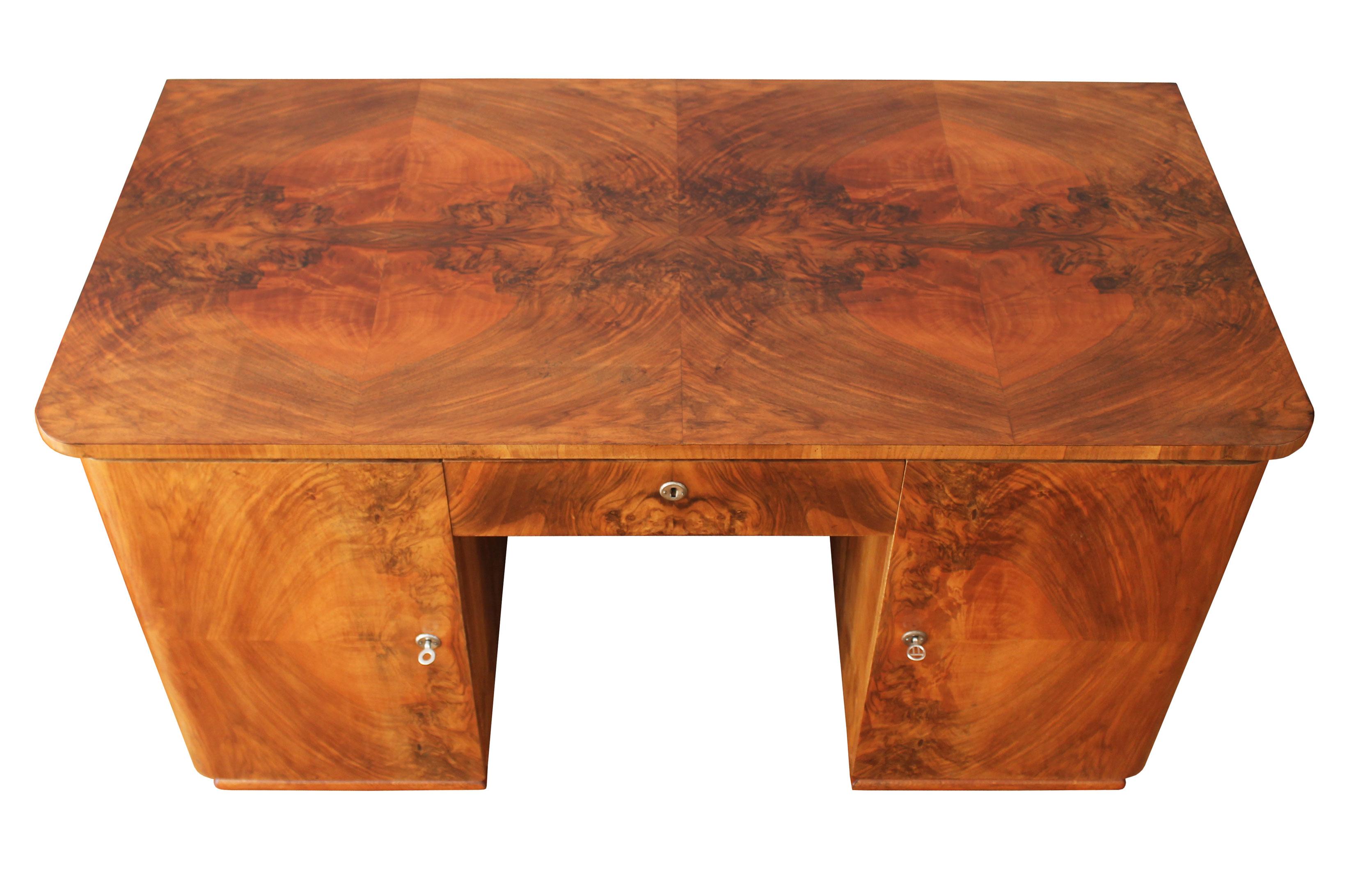 An original Art Deco desk from the 1940s. This piece has a dignified design with robust and stylish proportions and a dazzling Walnut pattern to it’s table top, sides, doors and drawers.

This writing / office desk has a rectangle table top with