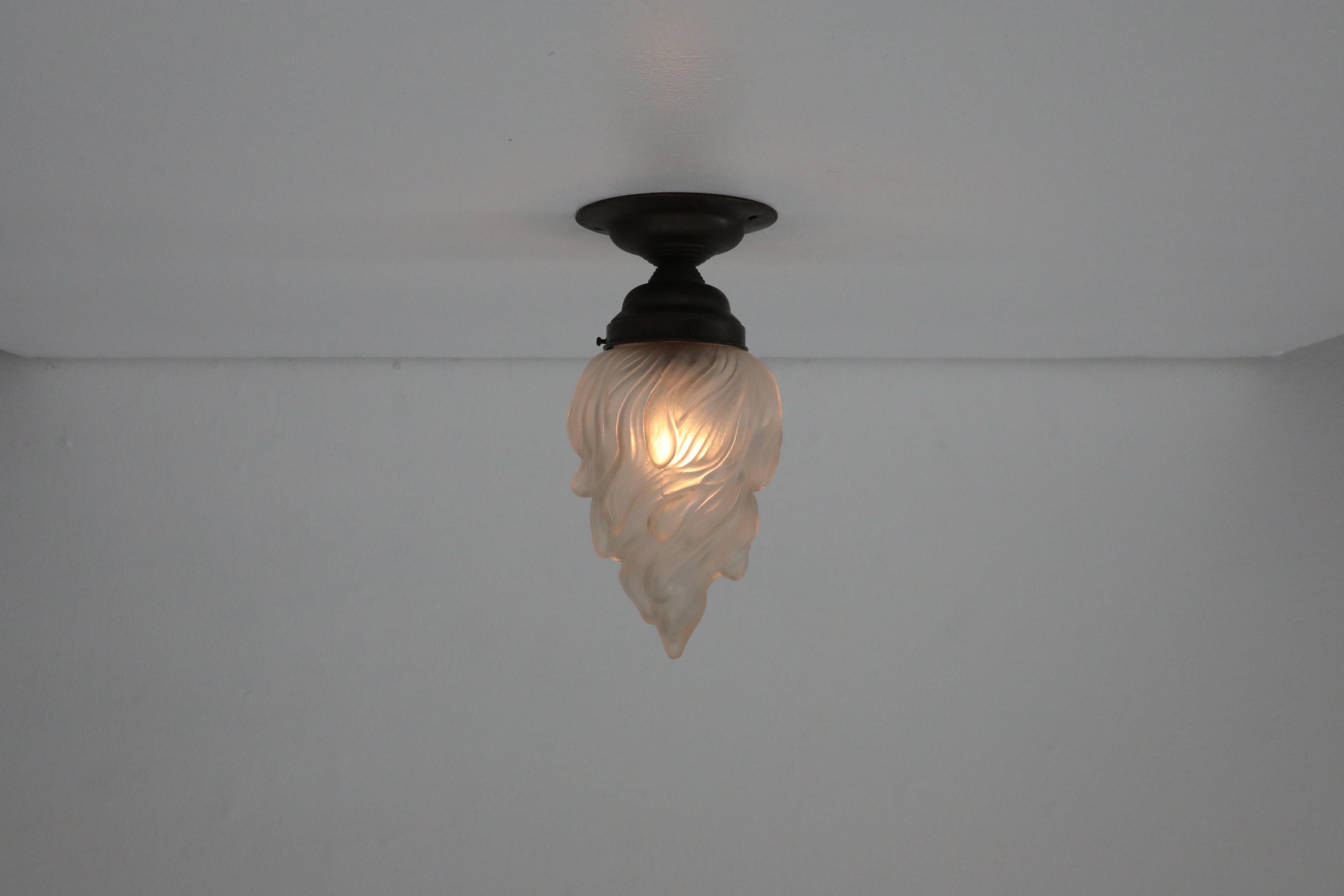 With its striking flame shaped, mold-blown frosted glass shade this ceiling or wall lamp is a wonderful piece of Art Deco lighting. Reminiscent of similar designs by Zenith, this piece marries elegance and functionality in an almost effortless way.