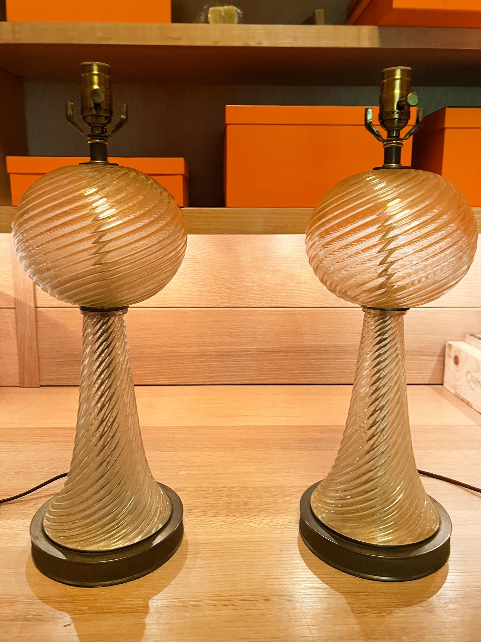 Fabriquées dans les années 1940, ces lampes de table exquises sont composées de corps en verre soufflé à la main, de bases en laiton et d'abat-jour en allumettes neuves. Le verre de Murano présente un élégant motif tourbillonnant qui donne à la