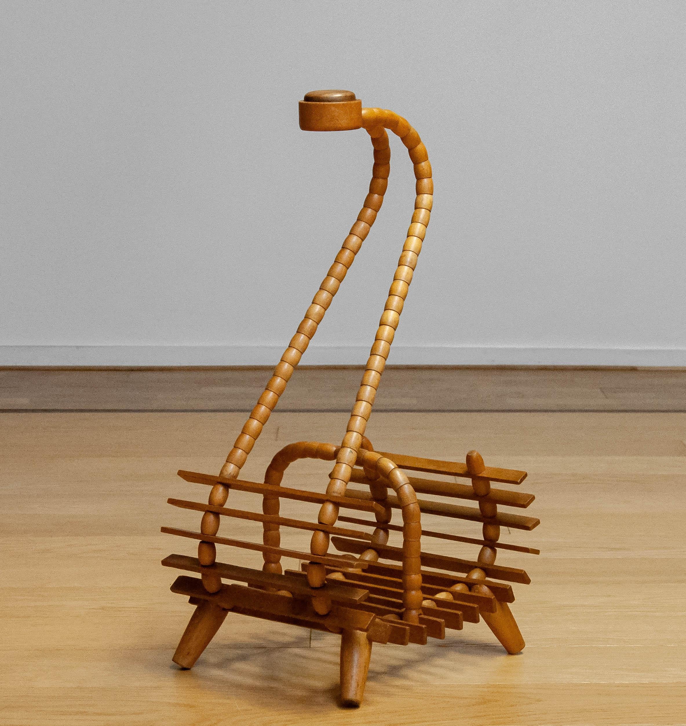 A sculptural 1940s magazine rack crafted from beech, featuring an elegantly curved handle inlaid with oak. The bentwood construction and splayed legs give it a distinctive mid-century character, combining lightness and functionality in a refined