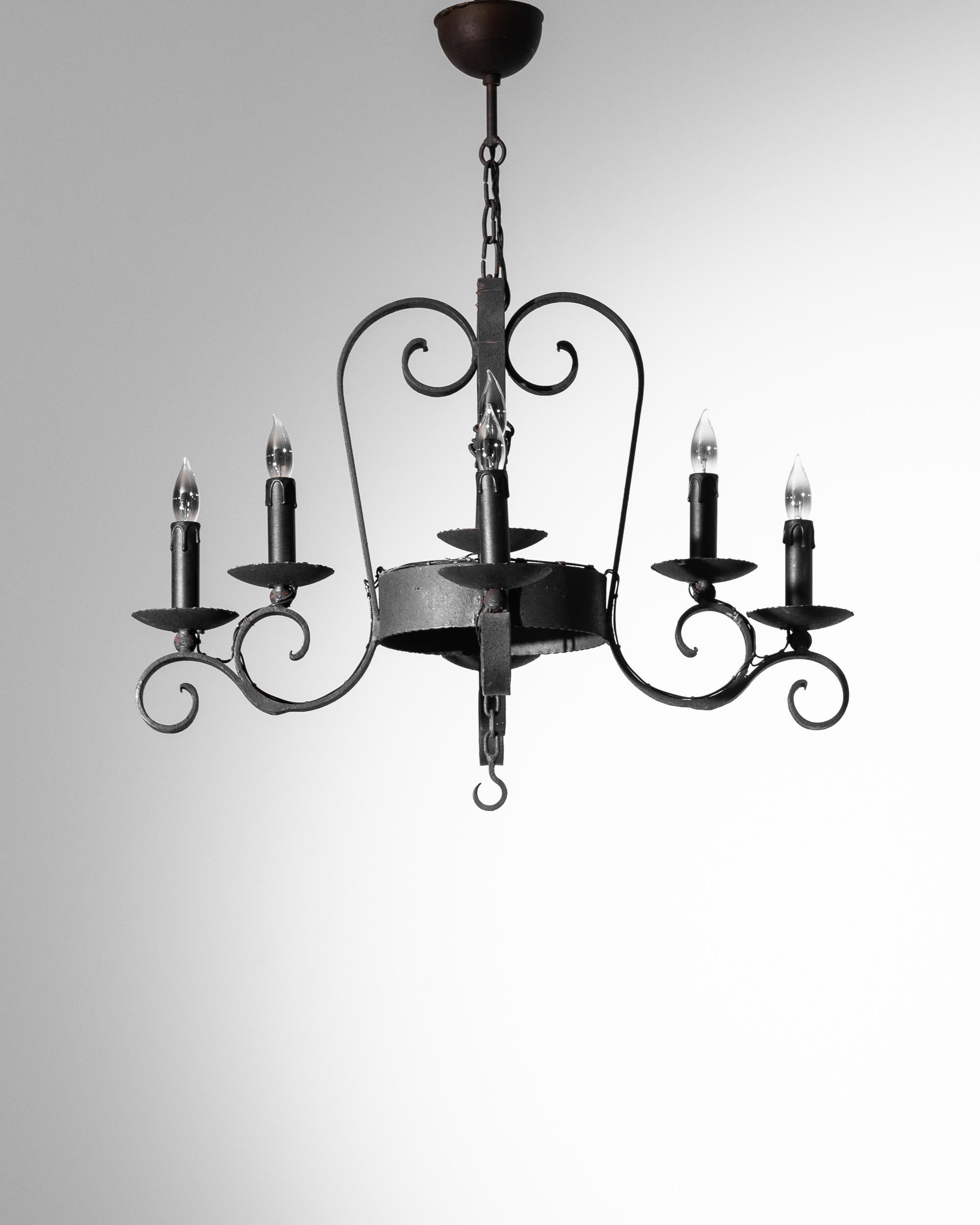 This vintage metal chandelier lends a note of gothic glamour to your space. Made in Belgium in the 1940s, a design of coiling wrought iron scrolls supports an arrangement of eight flame-shaped bulbs, throwing a striking shadow when illuminated. Mock
