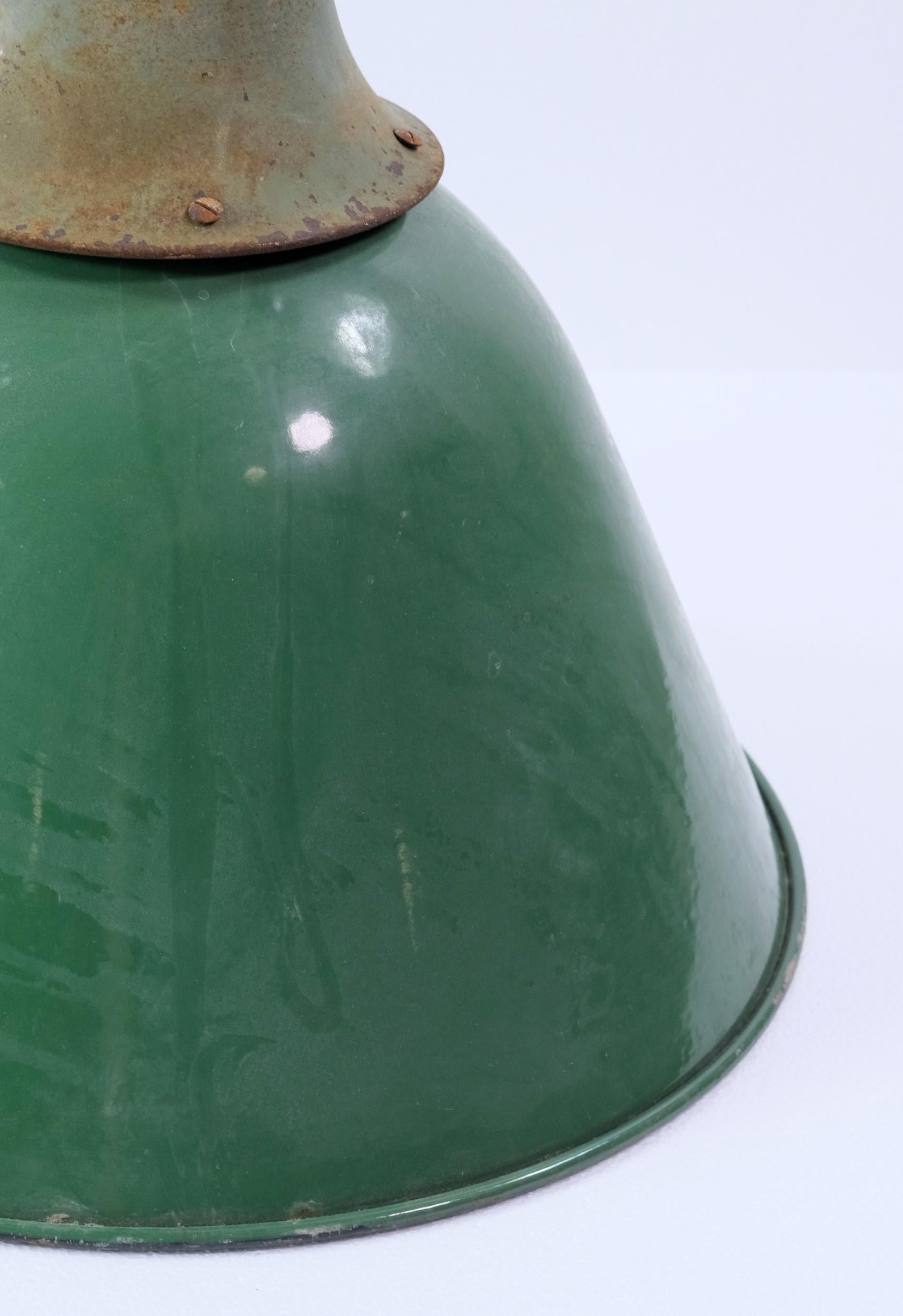 Industrial factory pendant light with green enamel shade which is white underneath.  This steel light originated from a 1940s factory and has a very long pole.  There is some rust and wear in the enamel (mostly underneath) which enhances its