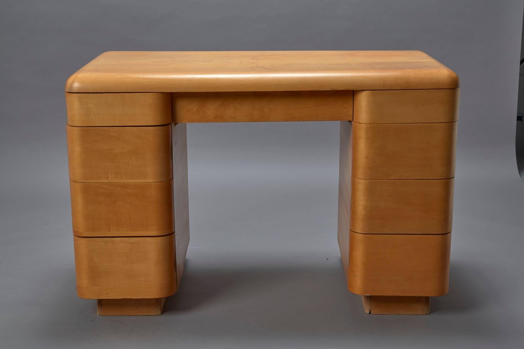 This Art Deco-style bentwood Mid-Century Modern writing desk was designed by Paul Goldman in 1946 for Plymold Co. This desk has eight drawers and one central long drawer that are flushed into the frame when closed.