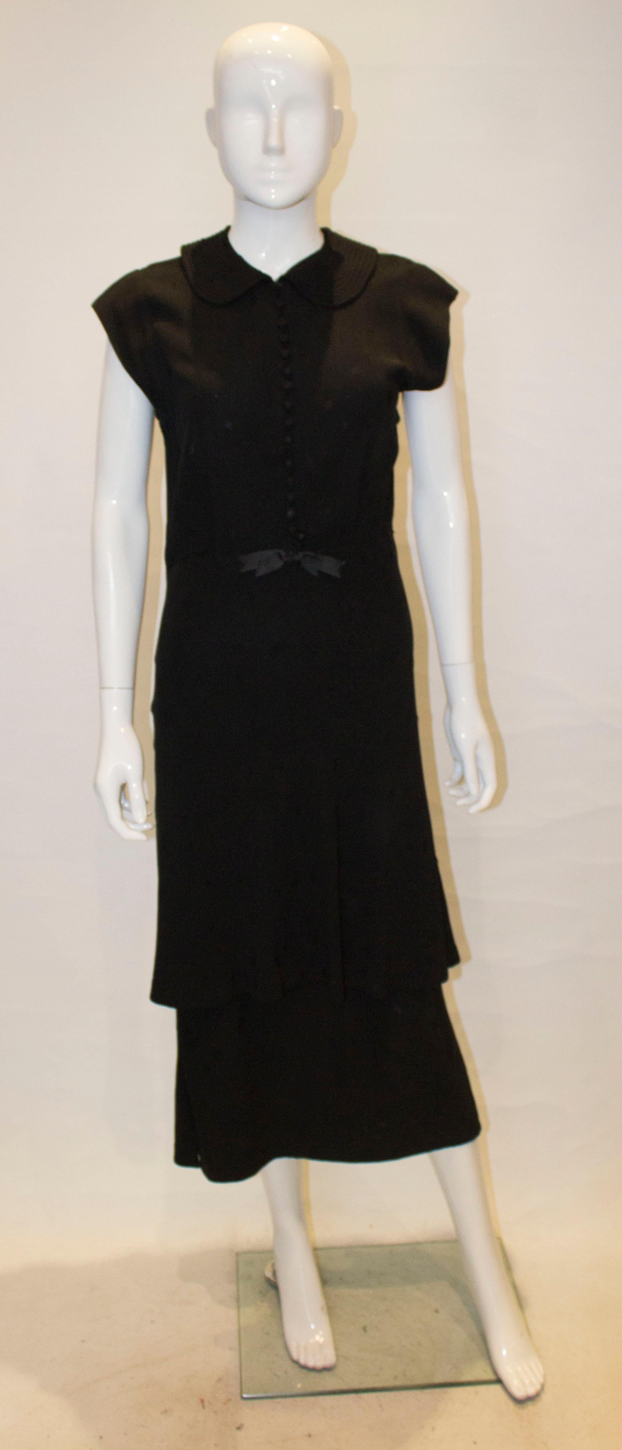 A chic vintage cocktail dress with a layered skirt and cap sleaves. The dress opens with fabric covered buttons at the front , and has an attractive stitched collar.