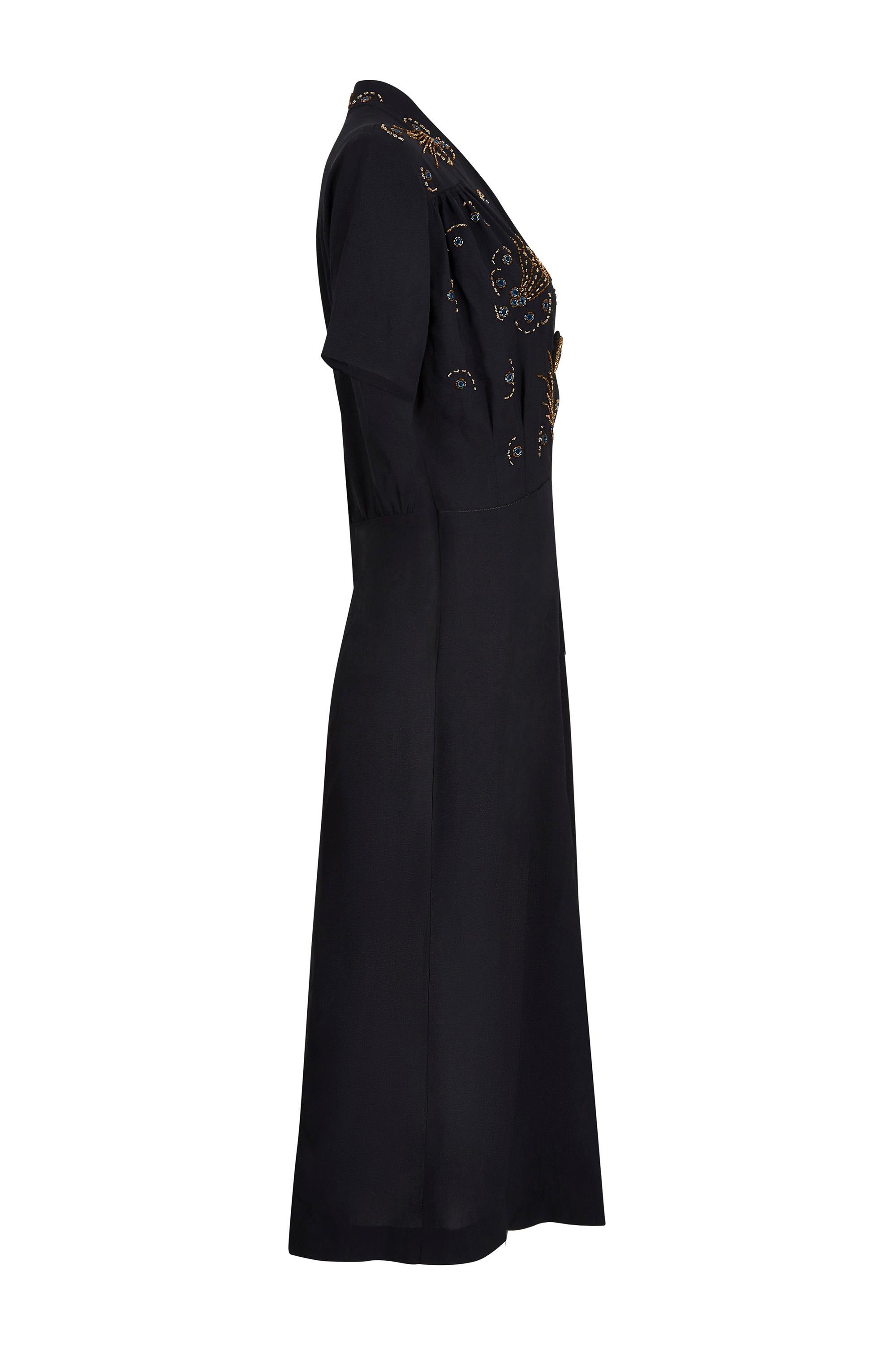 This desirable 1930s/late1940s black wool crepe dress is beautifully made and in exceptional vintage condition with no issues of any note. The dress is a simple shift cut with wide, elbow length sleeves, V-neckline and beaded cross over bodice. The