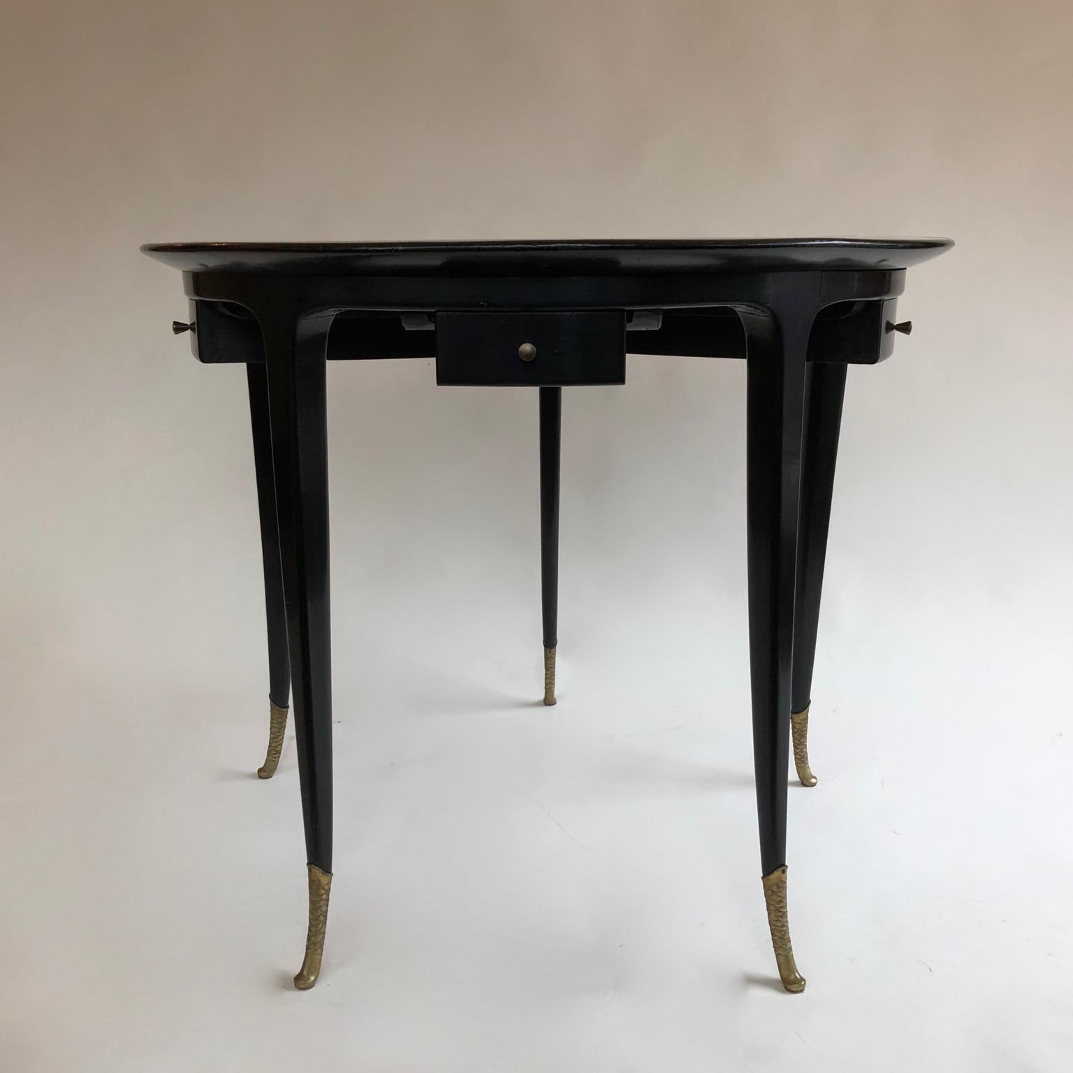 Superb 1940s circular black ebonised Italian games table with five small drawers, old black vinyl based top and elegant brass sabots. Black circular glass top available.
