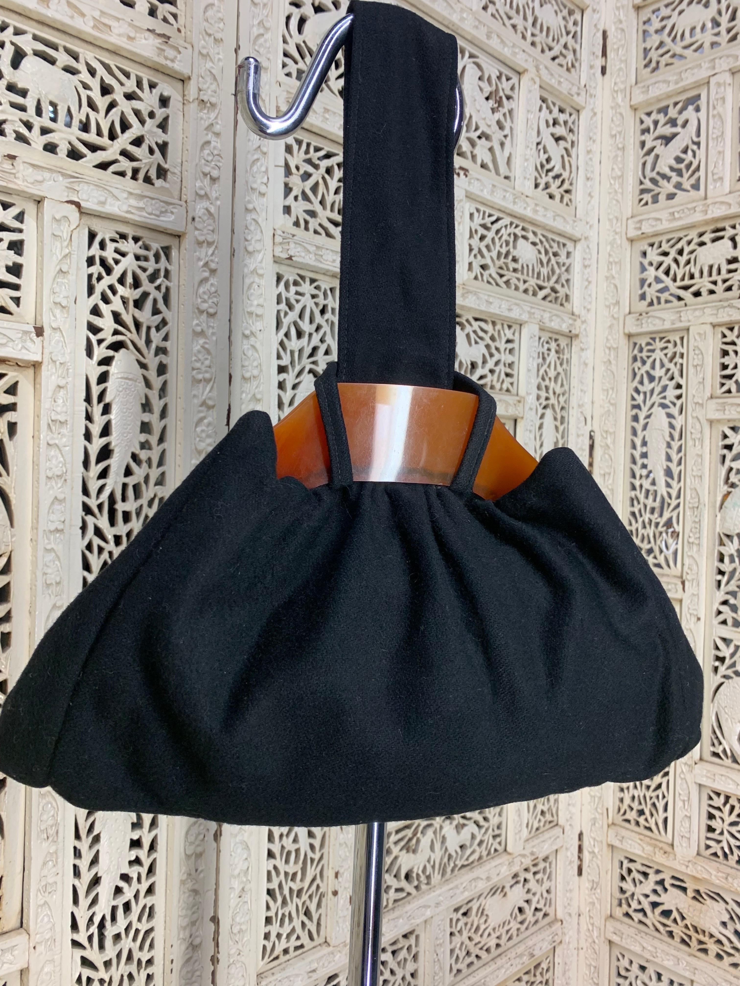 1940s Black Felt Handbag w Large Bakelite Frame and Loop Handle: Triangular shaped bag with single loop handle and pointed corners. Beautiful caramel color spring-hinged Bakelite frame. Black satin interior lining. Large sized capacity for a cell