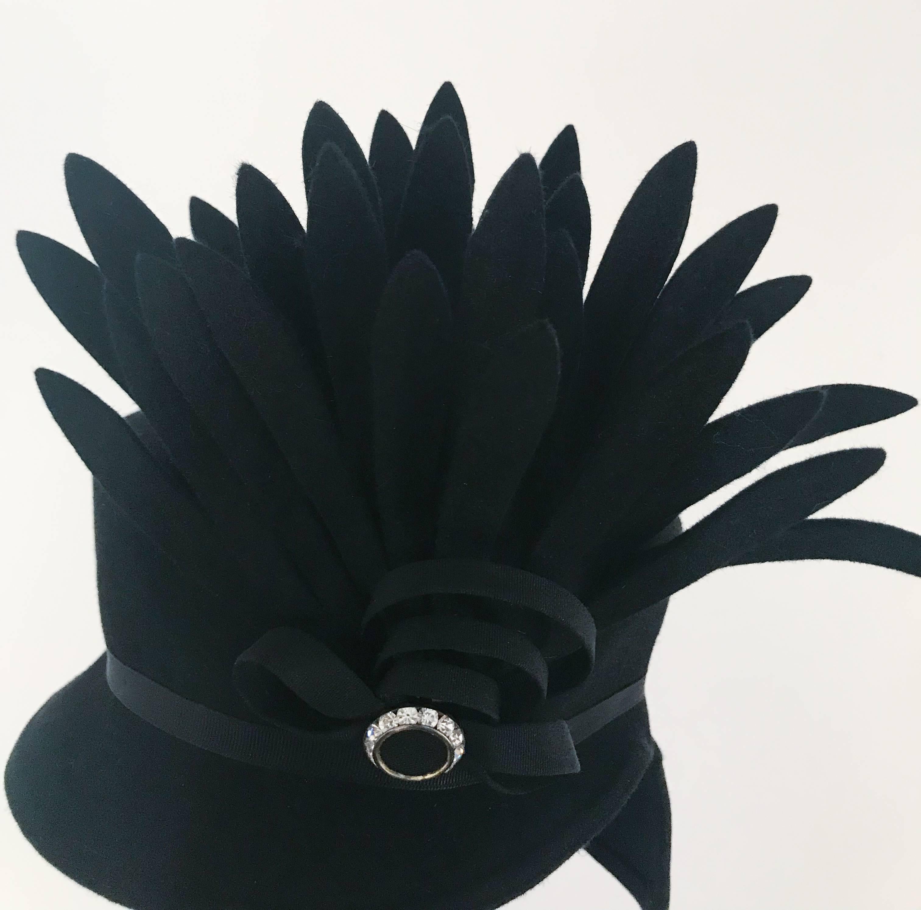 1940s Black Felt Toy Hat w/ Cut Feather Flourish. Toy hat perches towards side of head, rhinestone buckle decorates hatband while a delightful cascade of cut felt feathers embellish the side of the hat. Held to hat with elastic band at nape of neck. 