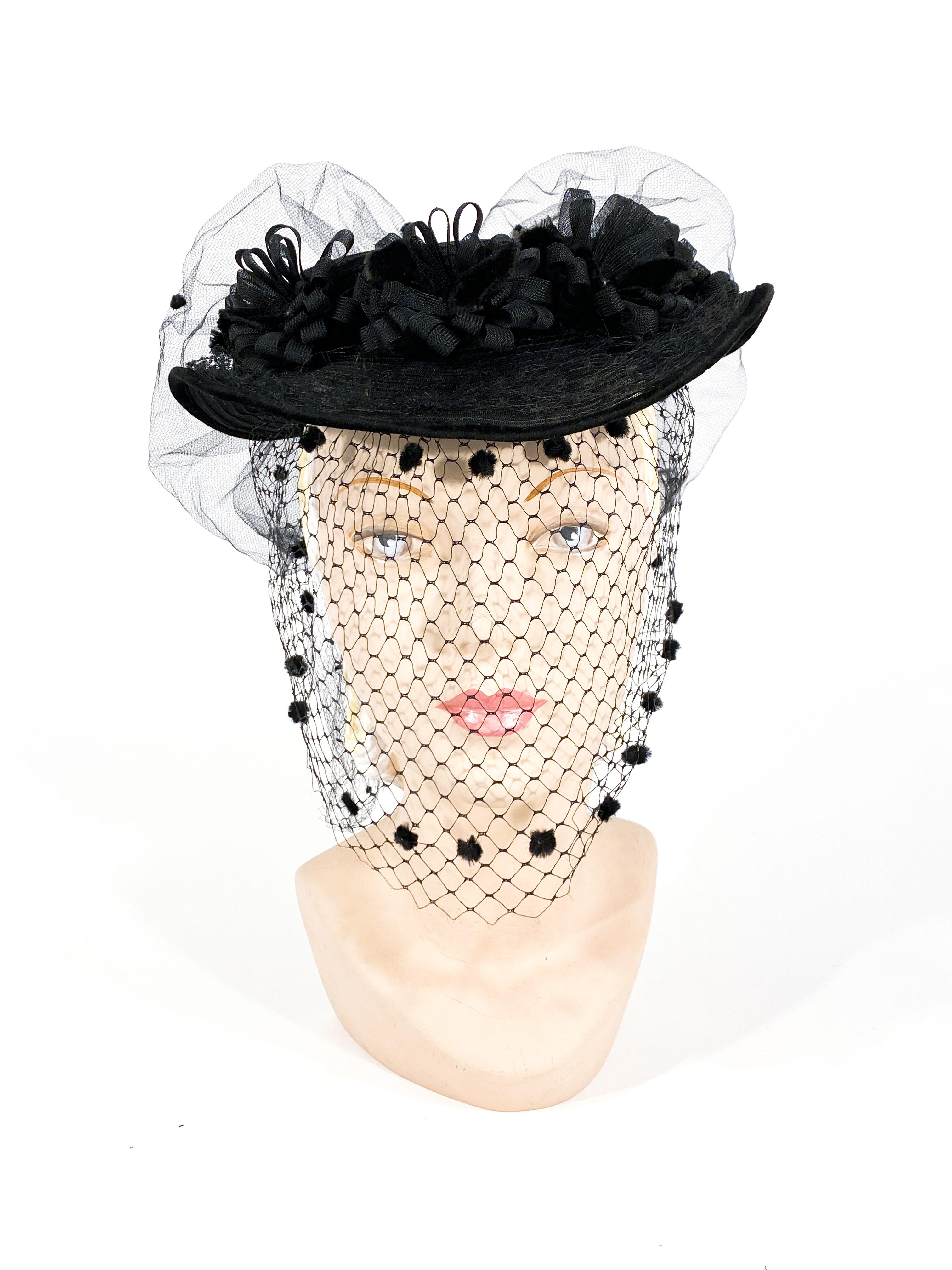 1940s black horse woven horse had sculpted hat with looped horsehair flower and a tilted brim. The black full-face veil is decorated with velvet dots at the very top of the head and under the chin to frame the face. The hat is finished with a large
