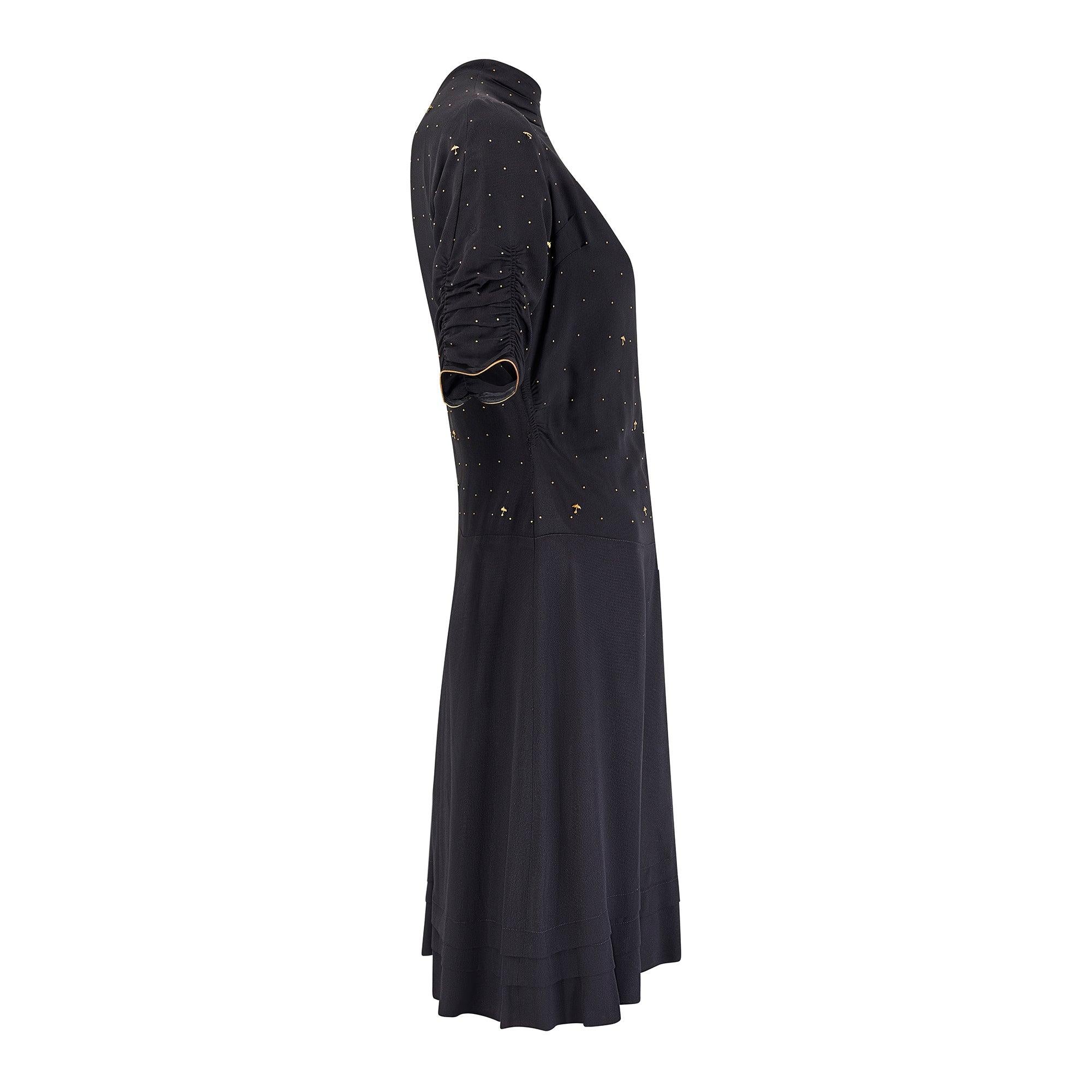 Este vestido de crepé de rayón negro y dorado de finales de los años 30 o principios de los 40 tiene delicadas tachuelas doradas en el corpiño en forma de pequeños paraguas.  Nunca hemos visto esto en otra pieza vintage y este diseño novedoso es