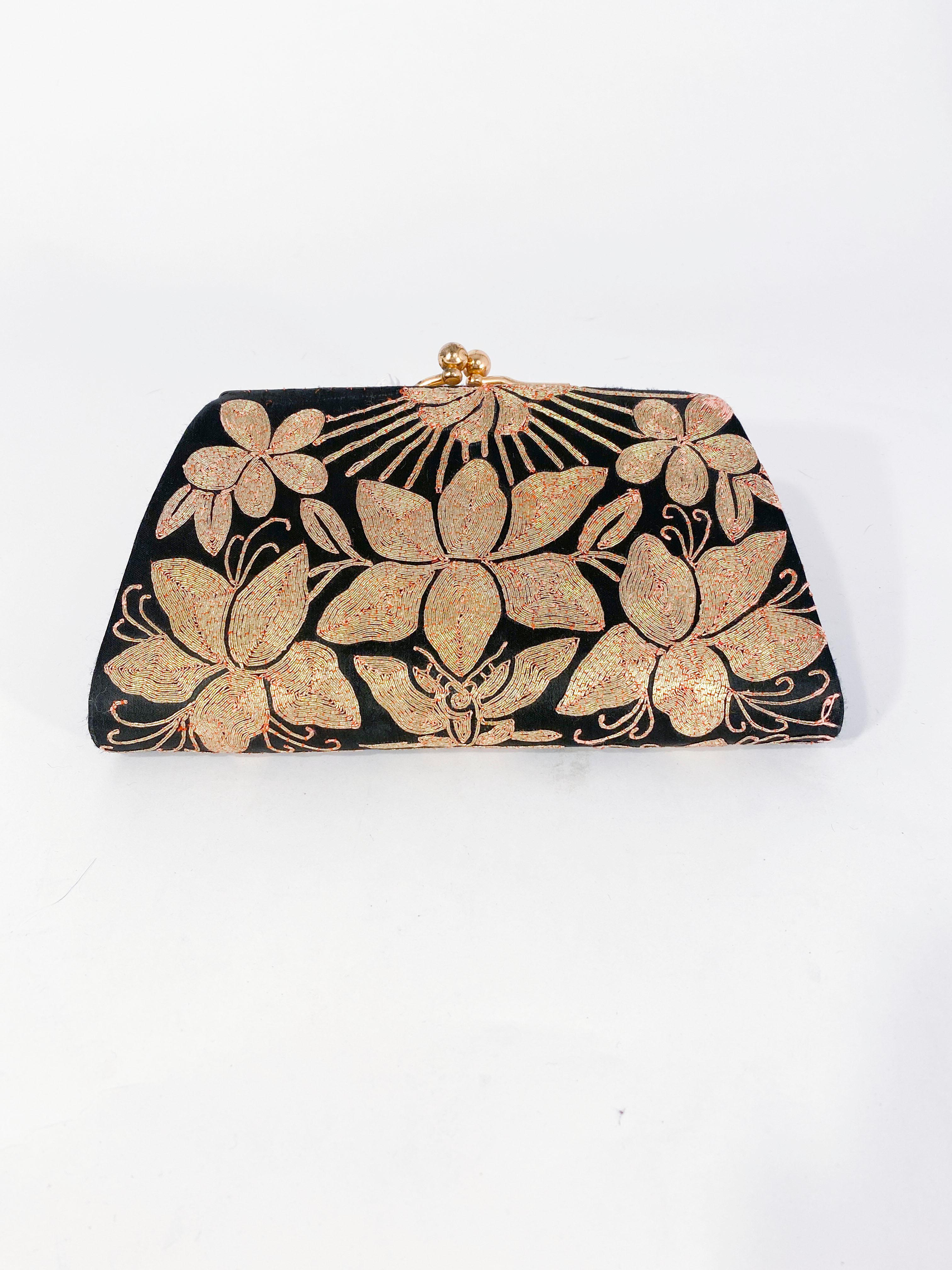 1940s black Satin evening clutch with decorative couched embroidery in metallic gold configured in flowers, butterfly, and sun-ray motifs. This type of Shusu embroidery is a traditional Japanese technique seen on Kimonos and other traditional