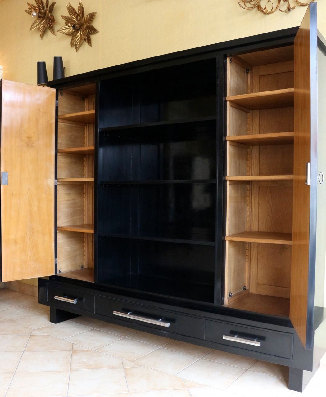 1940's bookcase by René Gabriel in black waxed lacquer, composed of two doors on each side of the furniture, the exterior in black lacquer, the interior in mahogany and equipped with adjustable shelves in height.
In the center of the cabinet, a
