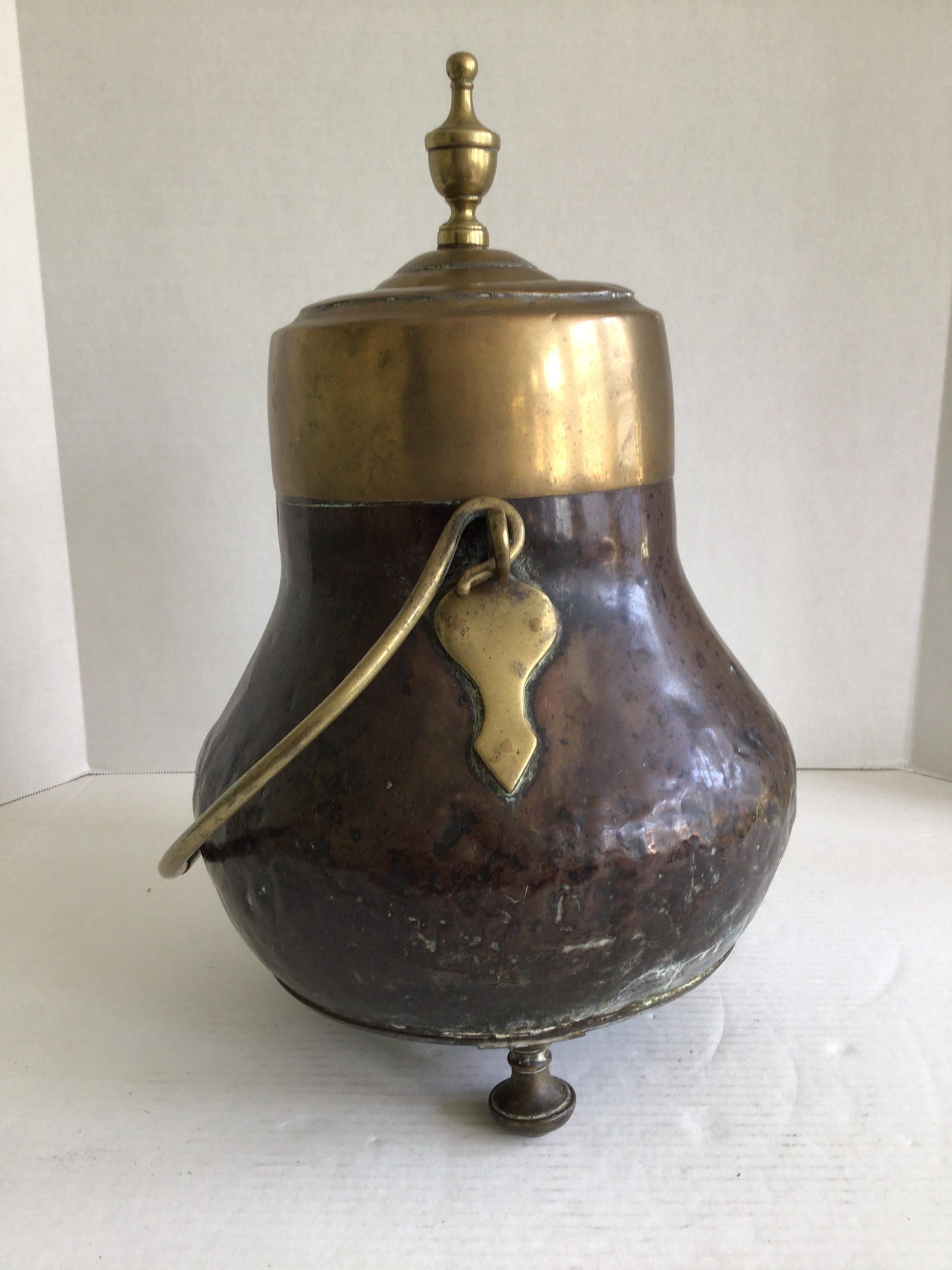 Calderone o bollitore con coperchio in ottone e rame degli anni '40 con manico e piedini in ottone
Piccole ammaccature in tutto 
Una delle saldature dei piedi è stata riparata (come mostrato nell'immagine)
