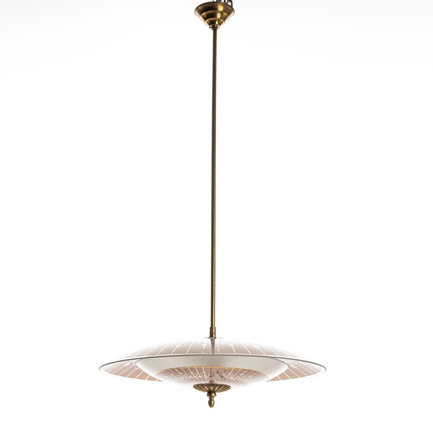 This wonderful piece consists of a brass frame connecting two unique frosted glass reflectors in pink. 
The lower glass reflector is accented with gold-colored rings and a stunning pattern. This mounts underneath a round, pink frosted glass