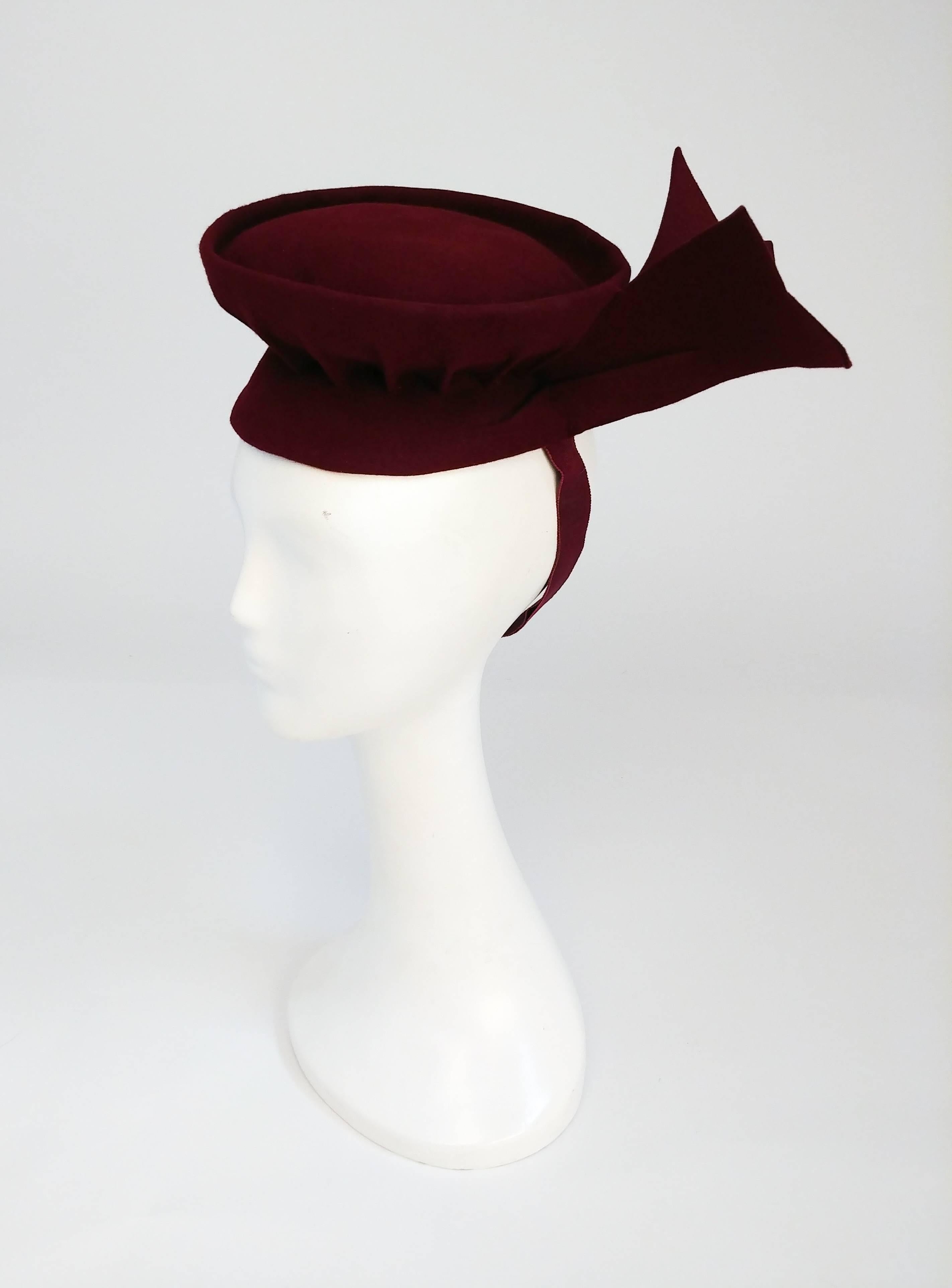 1940s Burgundy Felt Toy Hat. Burgundy wool felt toy hat with winged accents on the side and elasticated band.