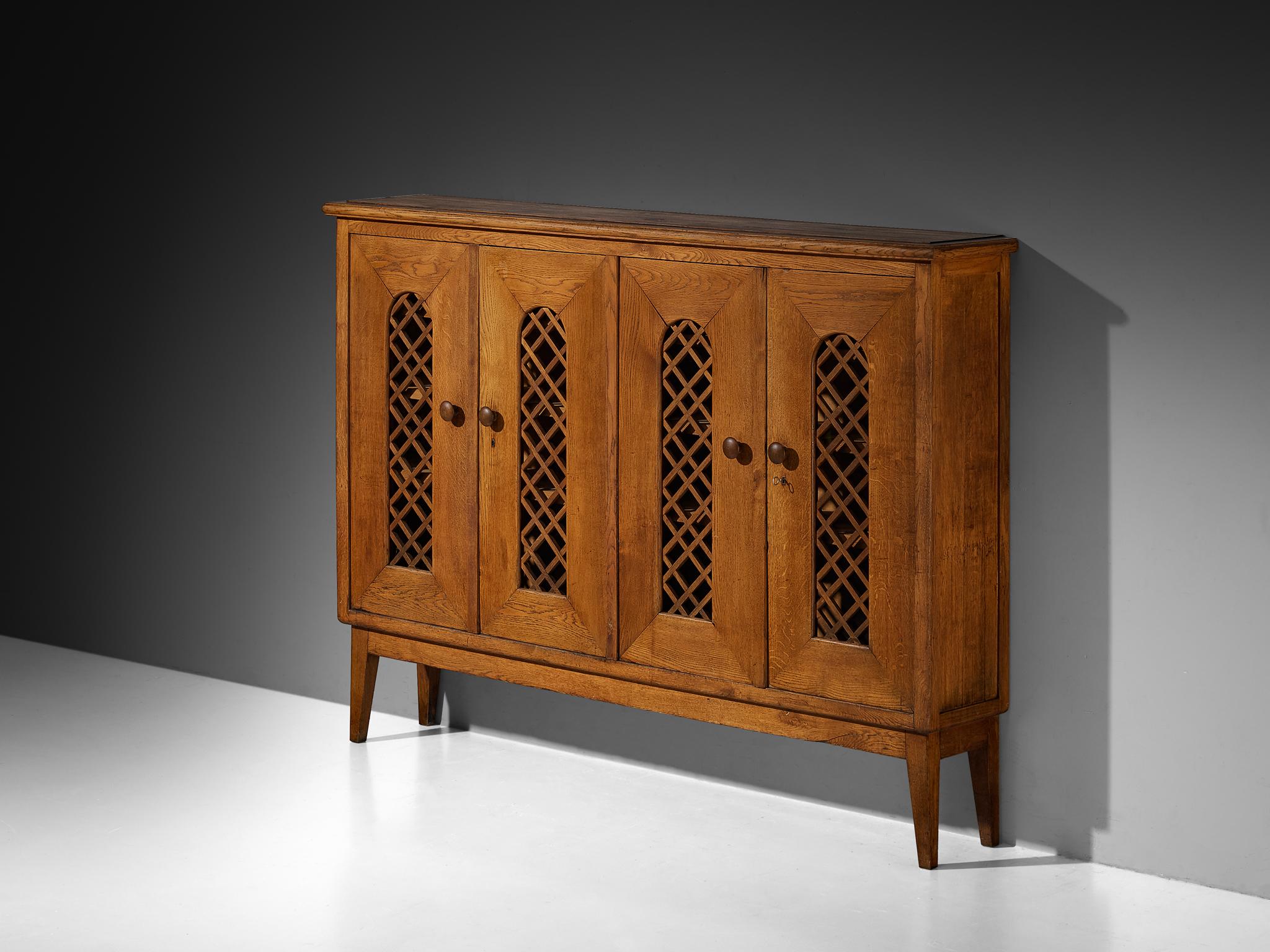 Cabinet, oak, glass, Italy, 1940s

A design that quietly bridges the gap between sleek modernism and handcrafted warmth. The cabinet’s facade is composed of four tall, narrow doors evenly spaced, each framed with an arched framework with latticework
