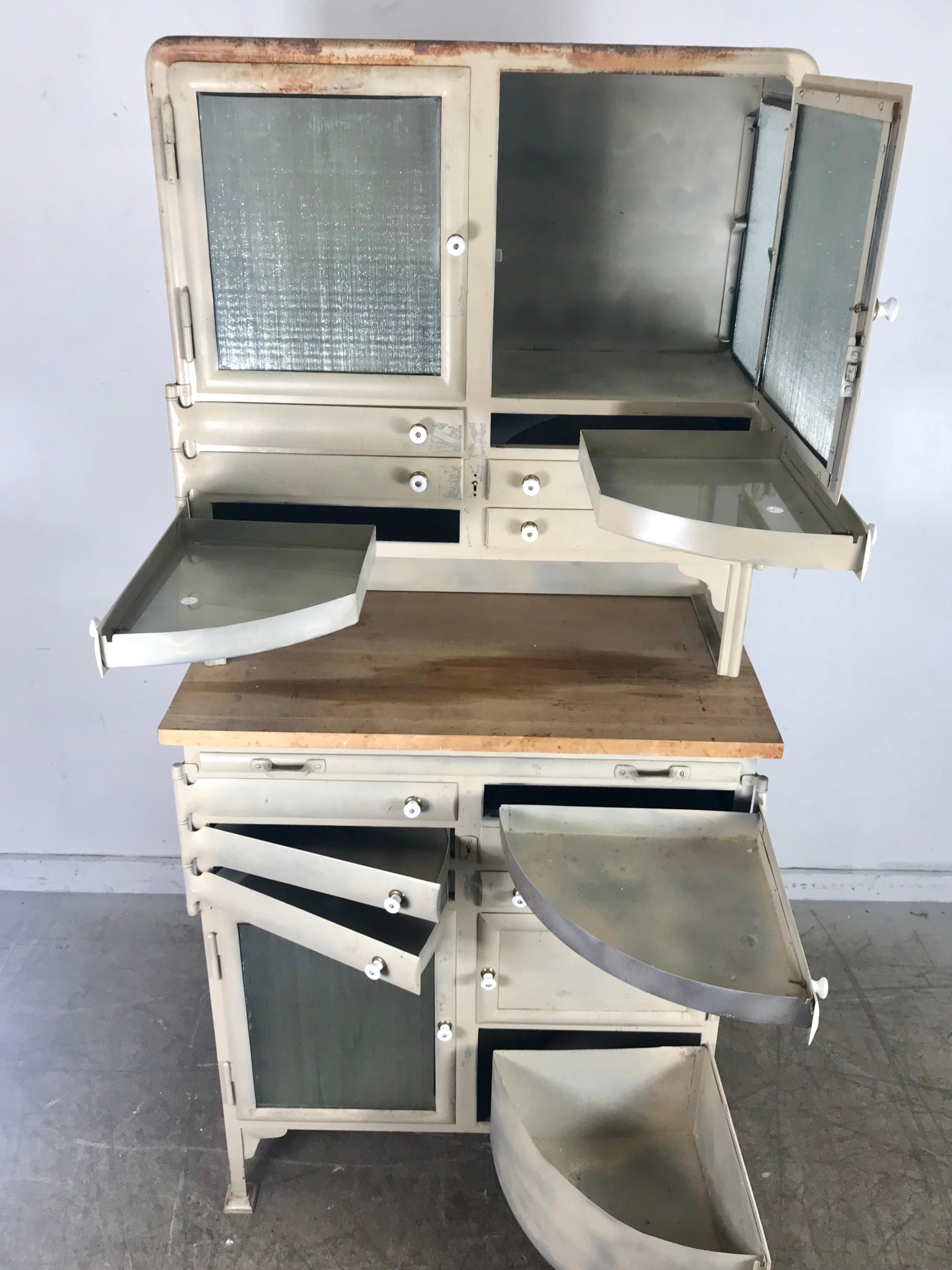 1940s cast steel industrial medical cabinet, multi pie wedge drawers and doors, old painted surface, wood top as well as pull-out wood work surface. Wonderful proportions and design, hand pulls have been replaced at some point in its life, retains