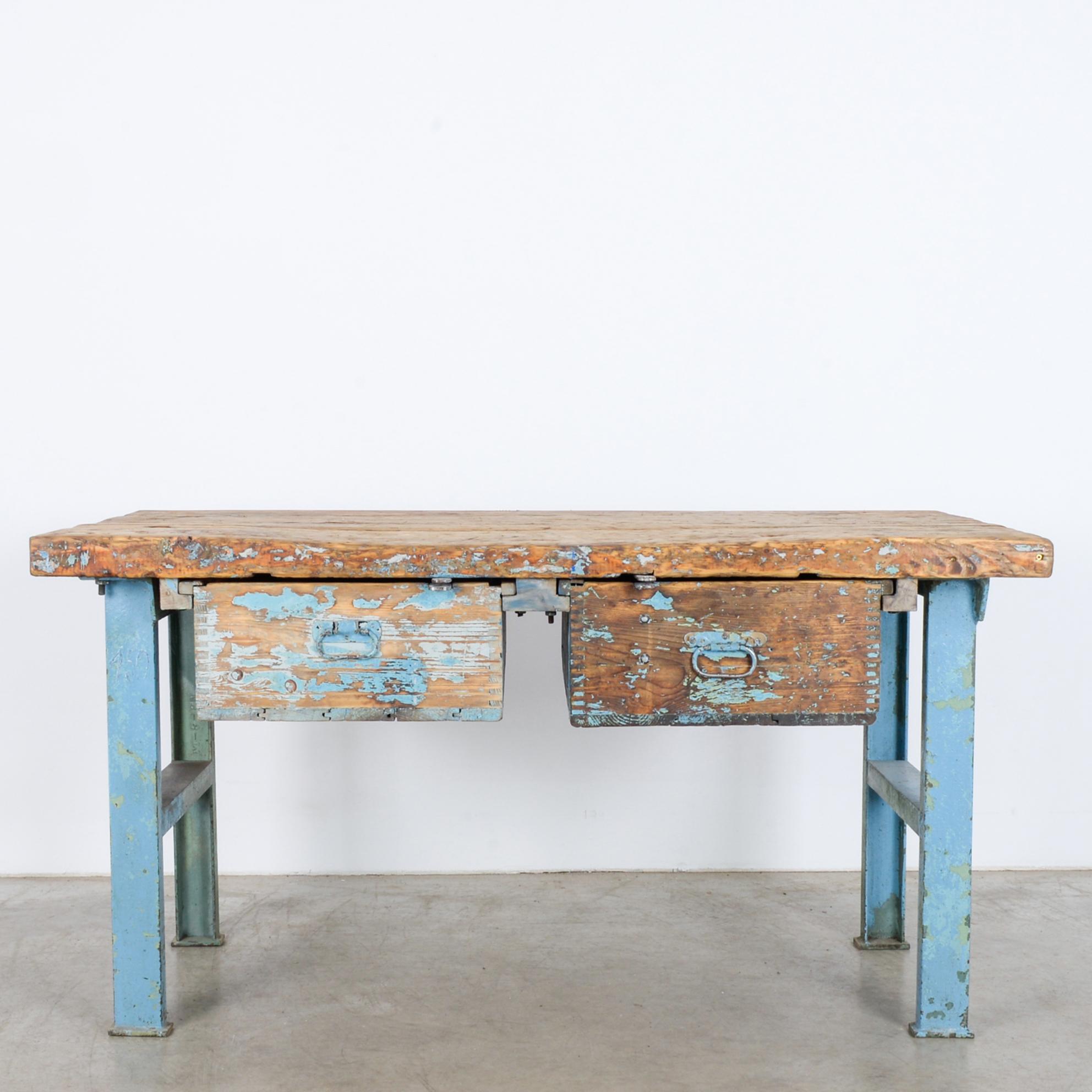 This worktable with two drawers was made in Central Europe, circa 1940. With sturdy, metal legs and a hand-hewn tabletop consisting of three hefty wooden planks, the table will lend a distinctive industrial vibe into any space. The distressed patina