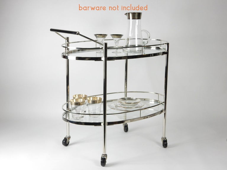 Fine quality bar trolley cart by Maxwell-Phillips of New York.
Oval shape, 2 tier glass shelf with thin guardrail edge.
Mirror finish chrome with brass screw and spacers.
Exception piece.