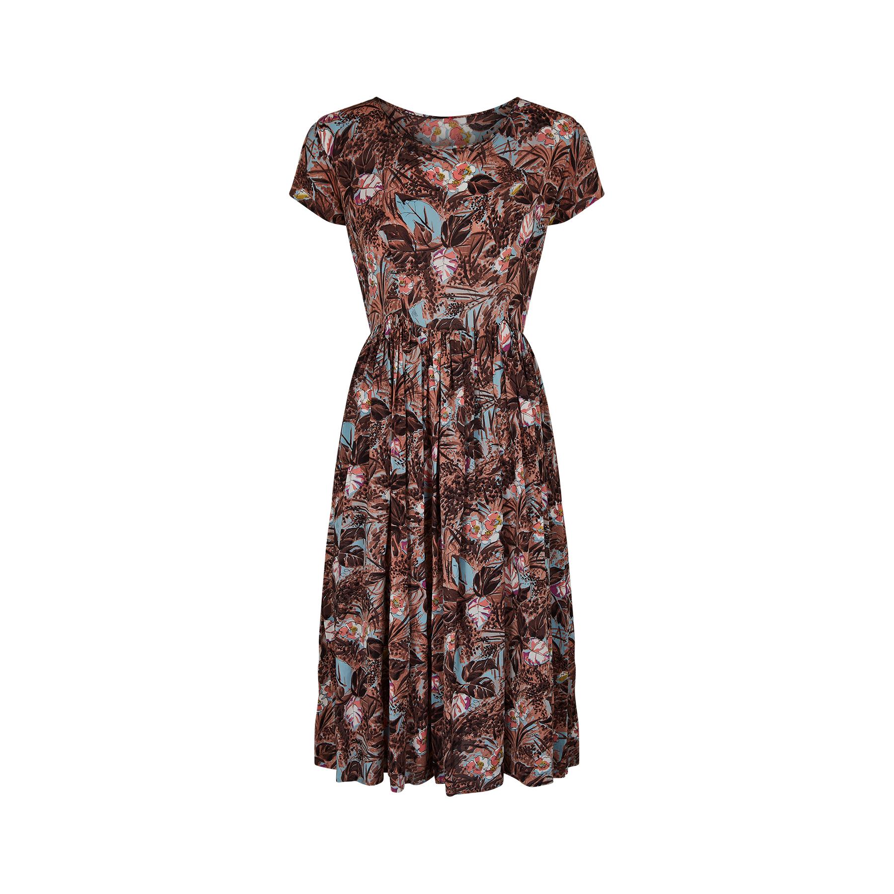 An original vintage cold rayon 1940s dress in a striking floral and leaf print.  The colour combination is a sublime contrast of pastel blue, pink and white against a dusky orange background with a painterly application of brown brush strokes which
