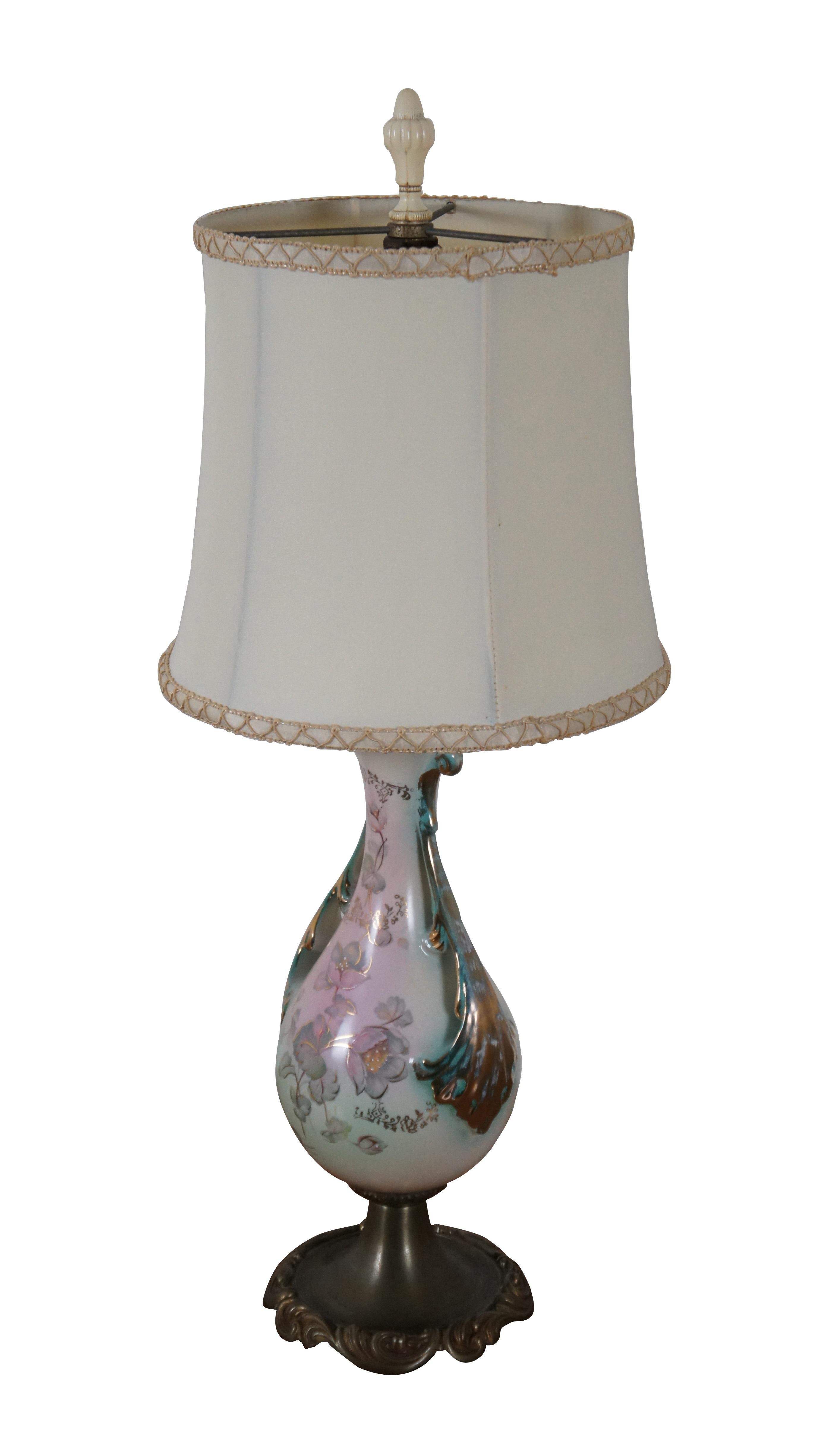 1940’s hand painted porcelain table lamp featuring trophy form with serpentine reticulated handles and Art Nouveau style metal base by Coronet. Features hand painted flowers on a pink and teal green ground, framed at the sides with gilded leaves.