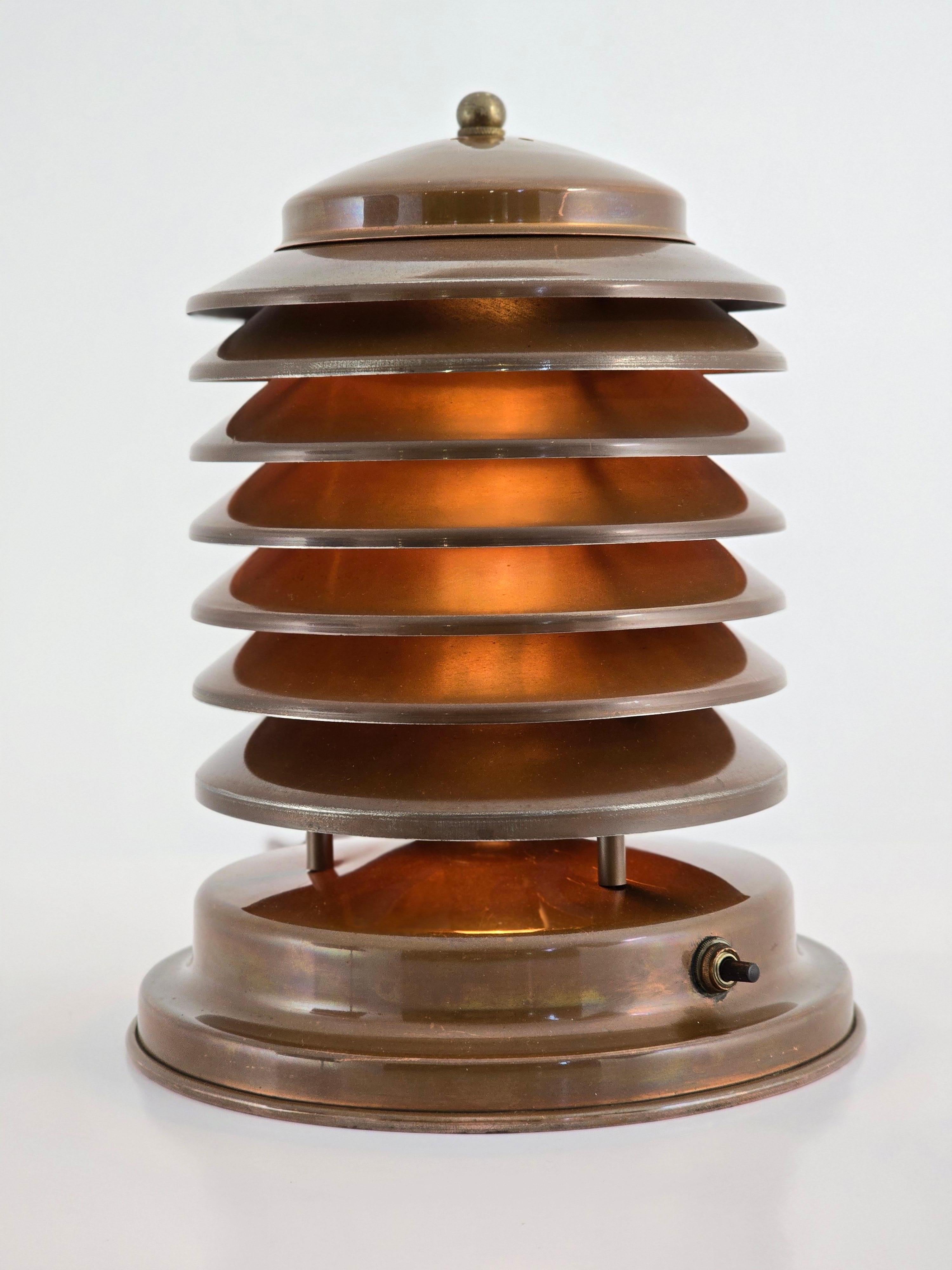 Icónica lámpara de sobremesa Coulter de siete niveles Art Déco, de la Edad de la Máquina. 

Ventilado  tapa  acceso a la bombilla. 

Interruptor giratorio de encendido/apagado en la base. 

Contiene una toma de tamaño E26 de 60 vatios. 

Pegatina de