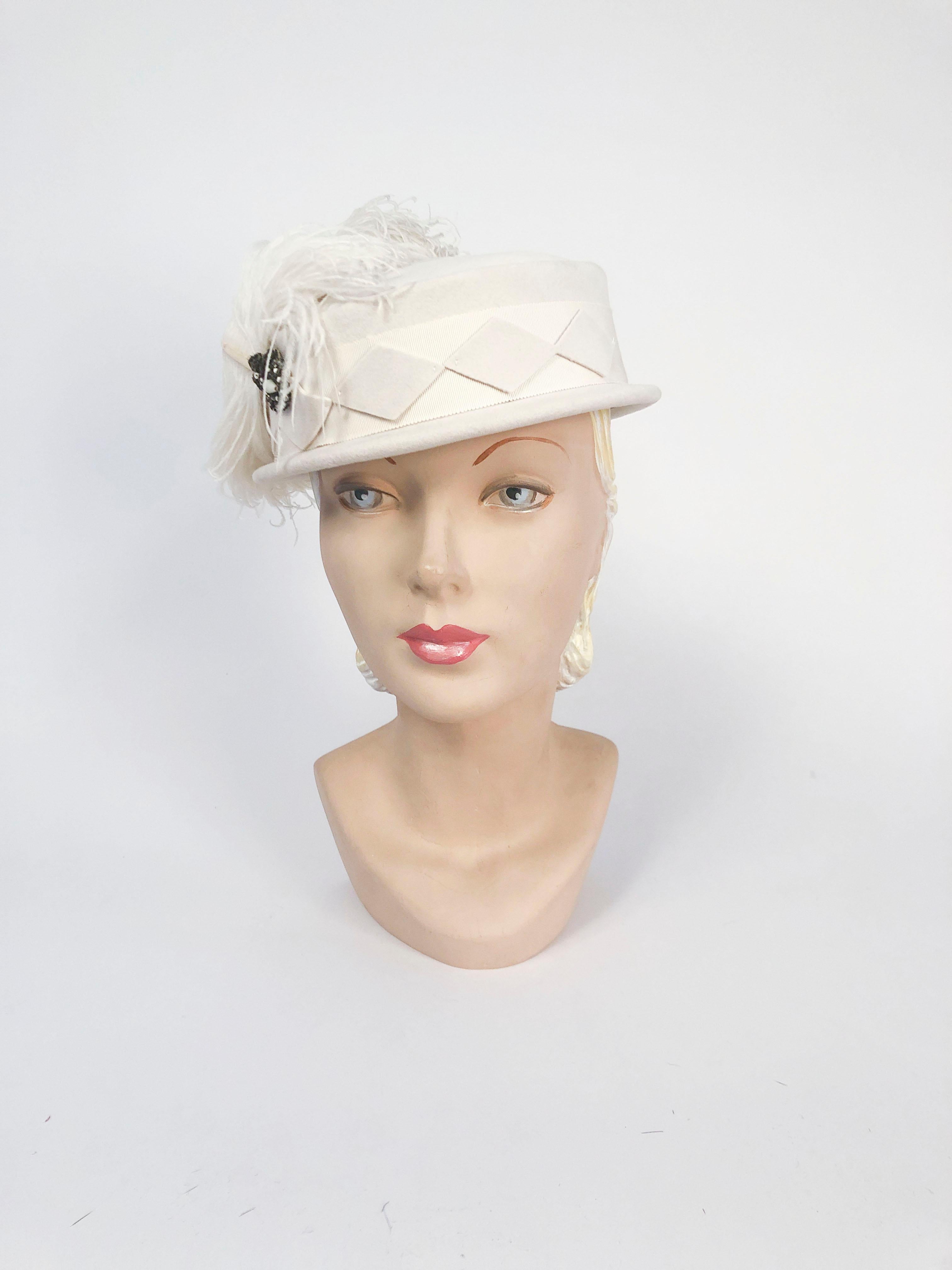 1940s Cream Fur Felt Hat with Wide Hat Band made of gros-grain, Diamond Applique along the band and hand-curled Feather that is large. The feather is held onto the hat with a metallic and glass beaded accent piece.