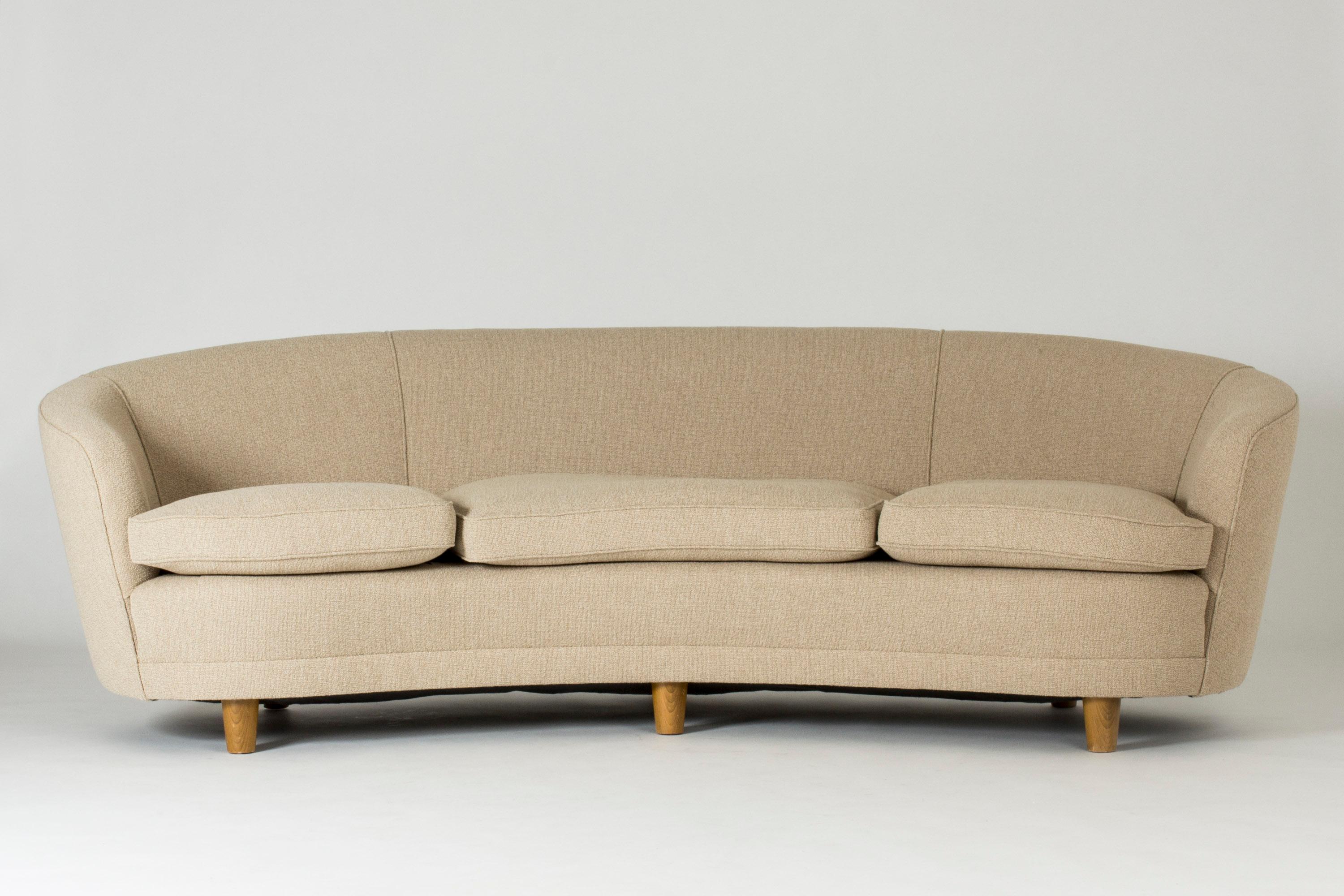 Large 1940s sofa, in a generous, curved design. Round, chunky wooden legs, bouclé fabric upholstery. Very elegant design, high quality and comfort.
