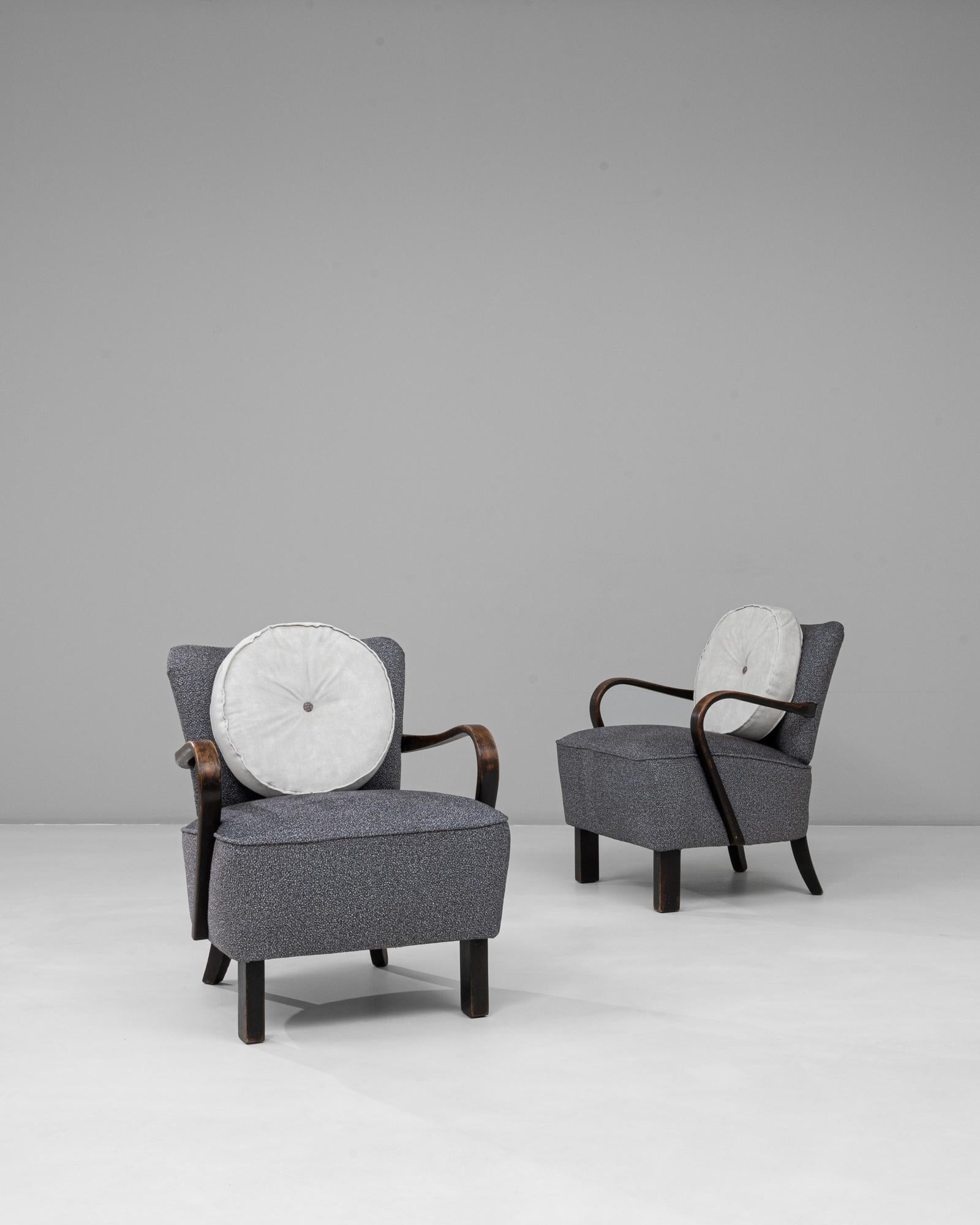 This elegant pair of 1940s Czech Art Deco upholstered armchairs captures the refined geometry and craftsmanship characteristic of the era. Featuring gracefully curved wooden arms and tapered legs, the chairs balance sculptural form with inviting