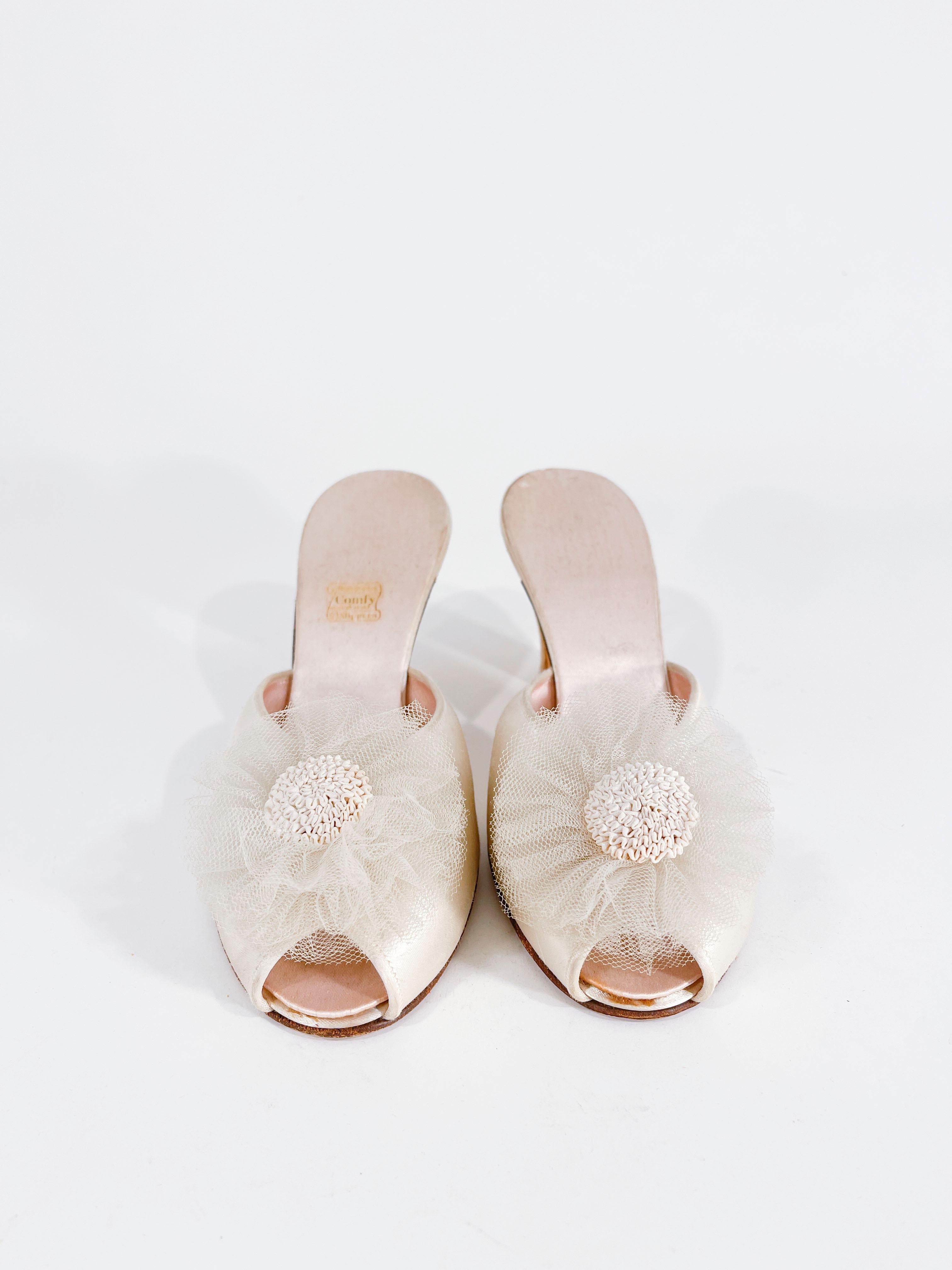 1940s Daniel Green champagne colored satin bedroom slippers with a handmade tulle flower and soustache ribbon center. The interior is also lined with matching champagne colored satin and the soles are made of leather. 