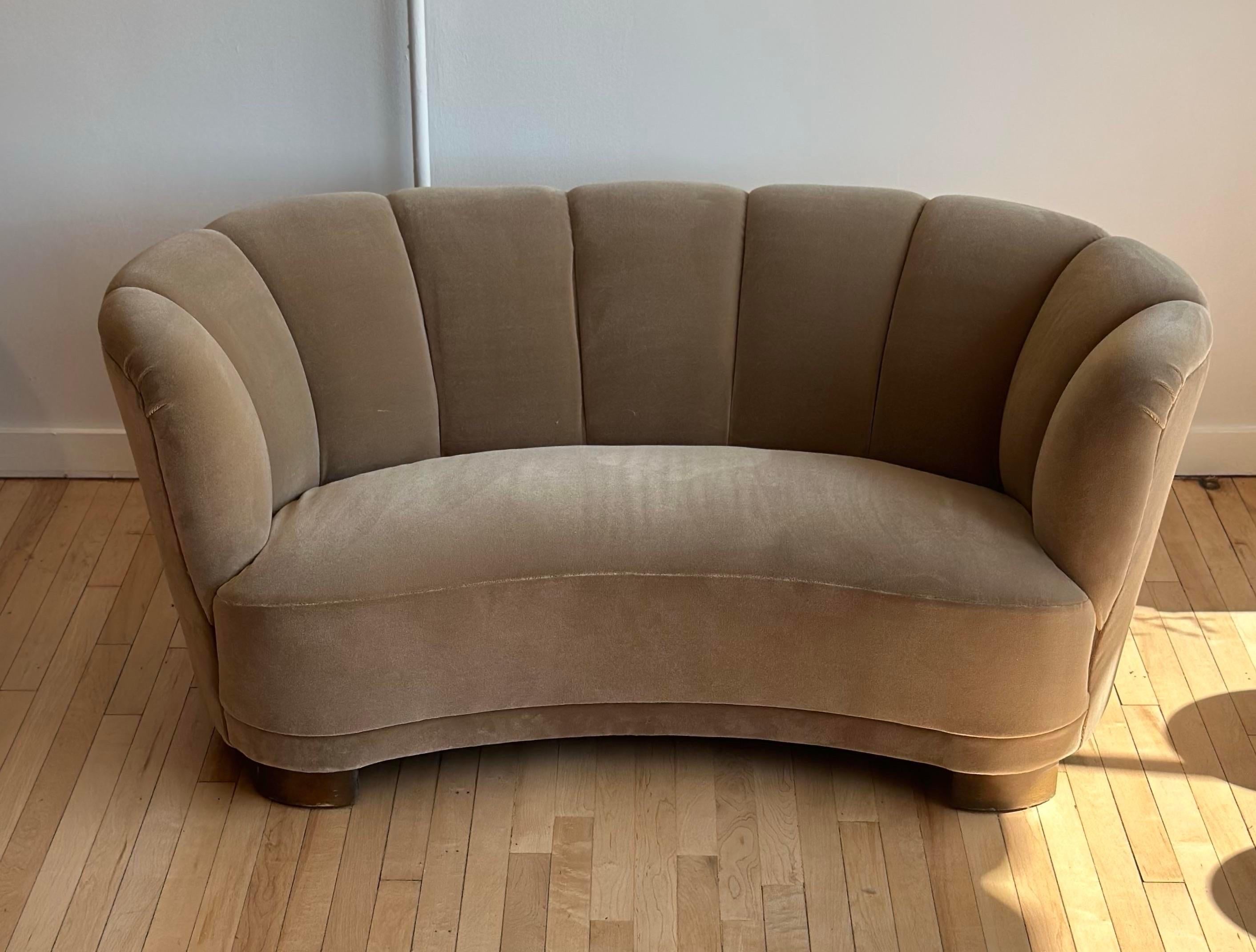 A curvaceous Danish banana sofa dating from the 1940’s. Recently upholstered in a light coffee colored mohair, features a rounded channel back and rounded seat.