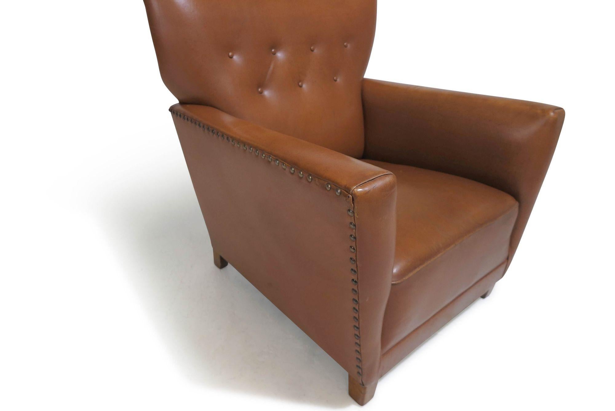 Early 1940's Danish lounge chair upholstered in the original brown leather with button tufted back, raised on stained walnut legs. Eight-way hand-tied copper springs under seat, horsehair padding, can be used as found or be completely reupholstered