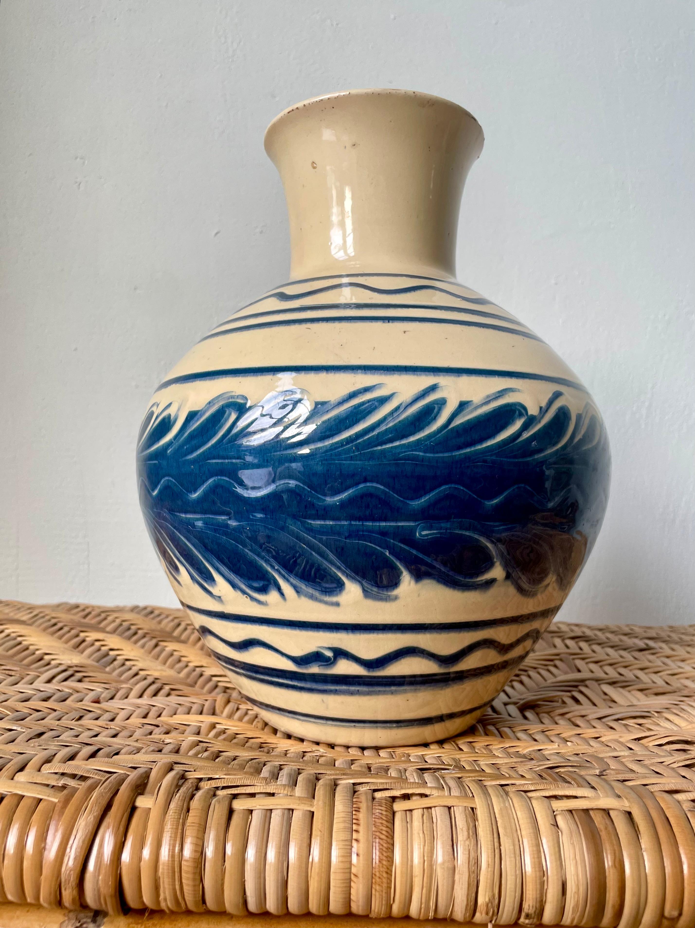 Handmade Danish 1940s ceramic vase by Herman Kähler Keramik. Cream glaze with hand-painted lined and organically wavy decorations in clear blue. Signed and stamped under base. Rustic vintage condition consistent with age and wear. 
Denmark, 1940s. 