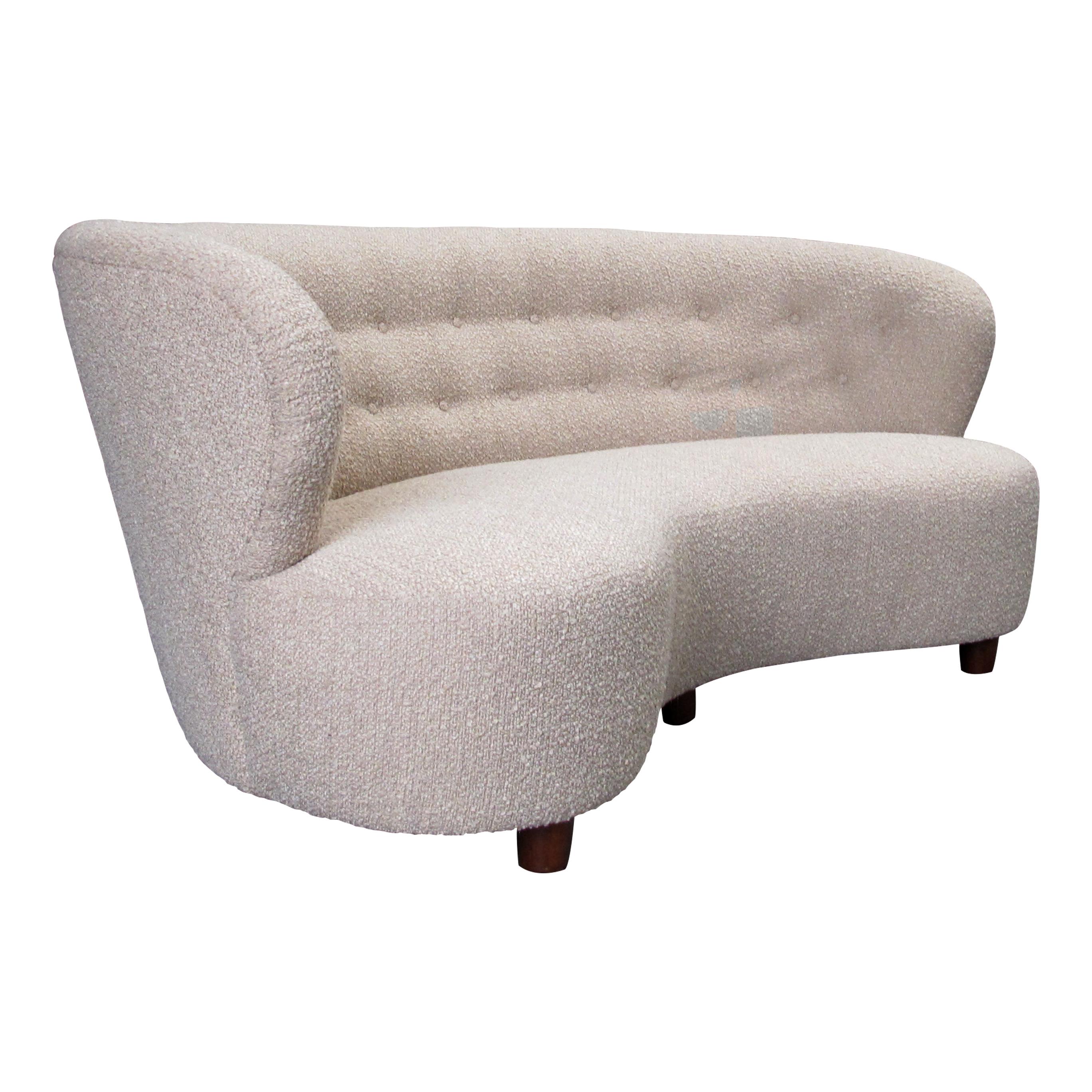 This comfortable large sofa is a classic Danish modern design from the 1940s. It has a simple, elegant design with clean lines and a curved back. The oak frame is sturdy and well-made, and the new short-pile boucle fabric upholstery is soft and
