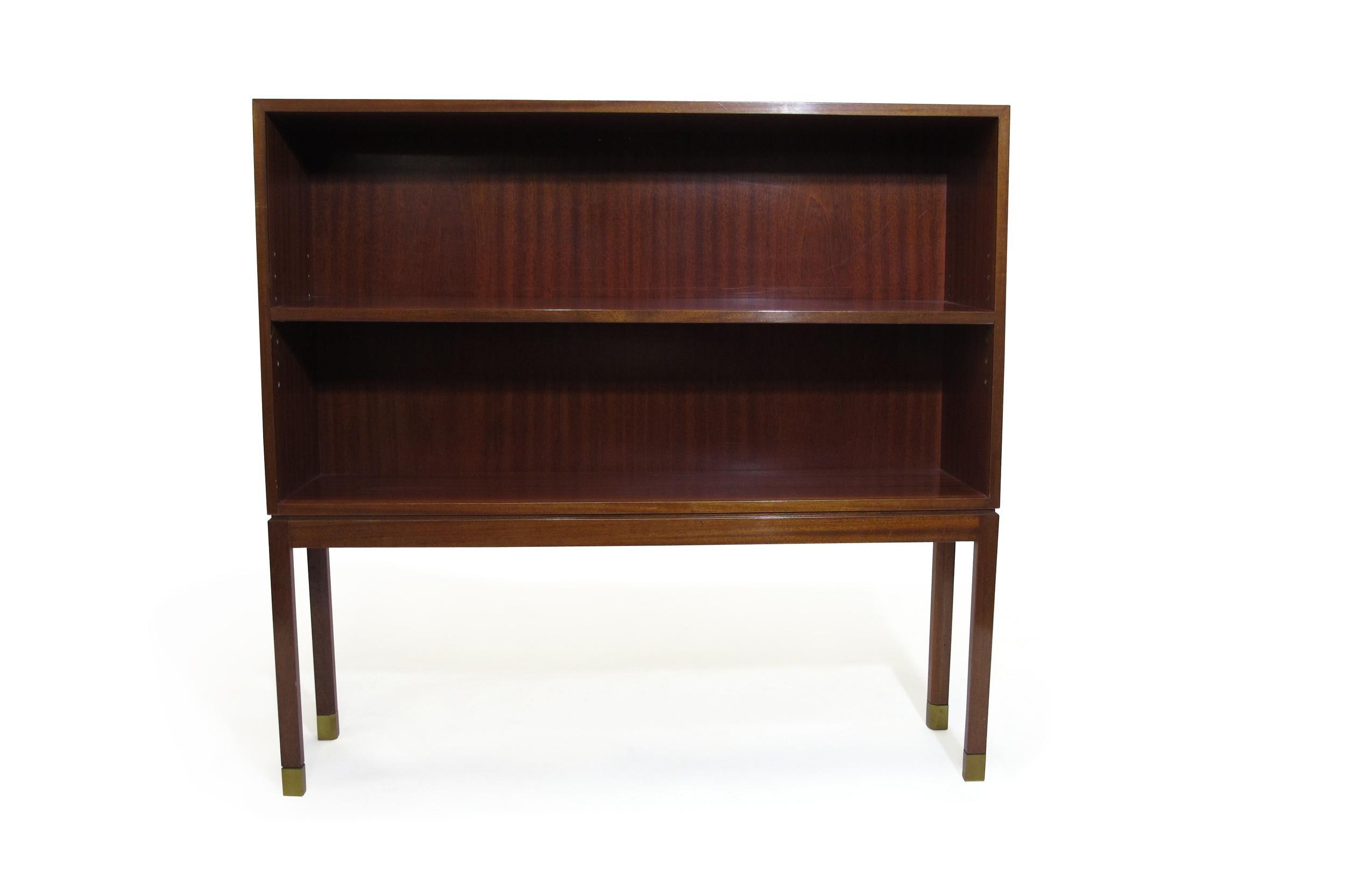 Bookcase attributed to Ole Wanscher for A. J Iversen crafted of Cuban mahogany with finely miter edges, raised on stilted legs with brass caps, and retains its original shellac finish, showing minor age-appropriate wear. Interior depth 11.25 inch