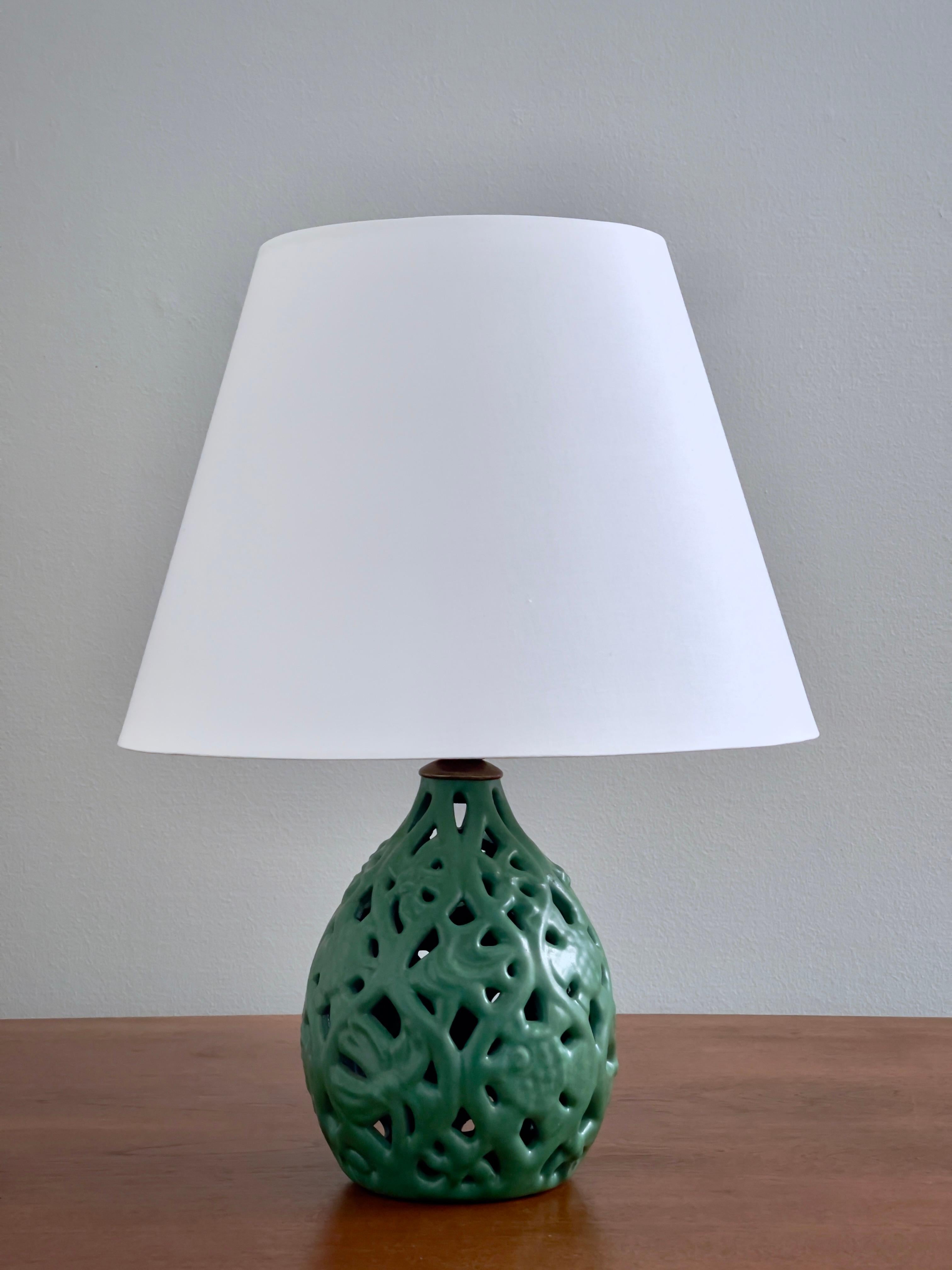Esta rara lámpara de sobremesa, fabricada por el estimado ceramista danés Michael Andersen & Son en la década de 1940, ejemplifica la fusión de forma y función que define el diseño escandinavo. La pieza presenta un motivo orgánico, representado con