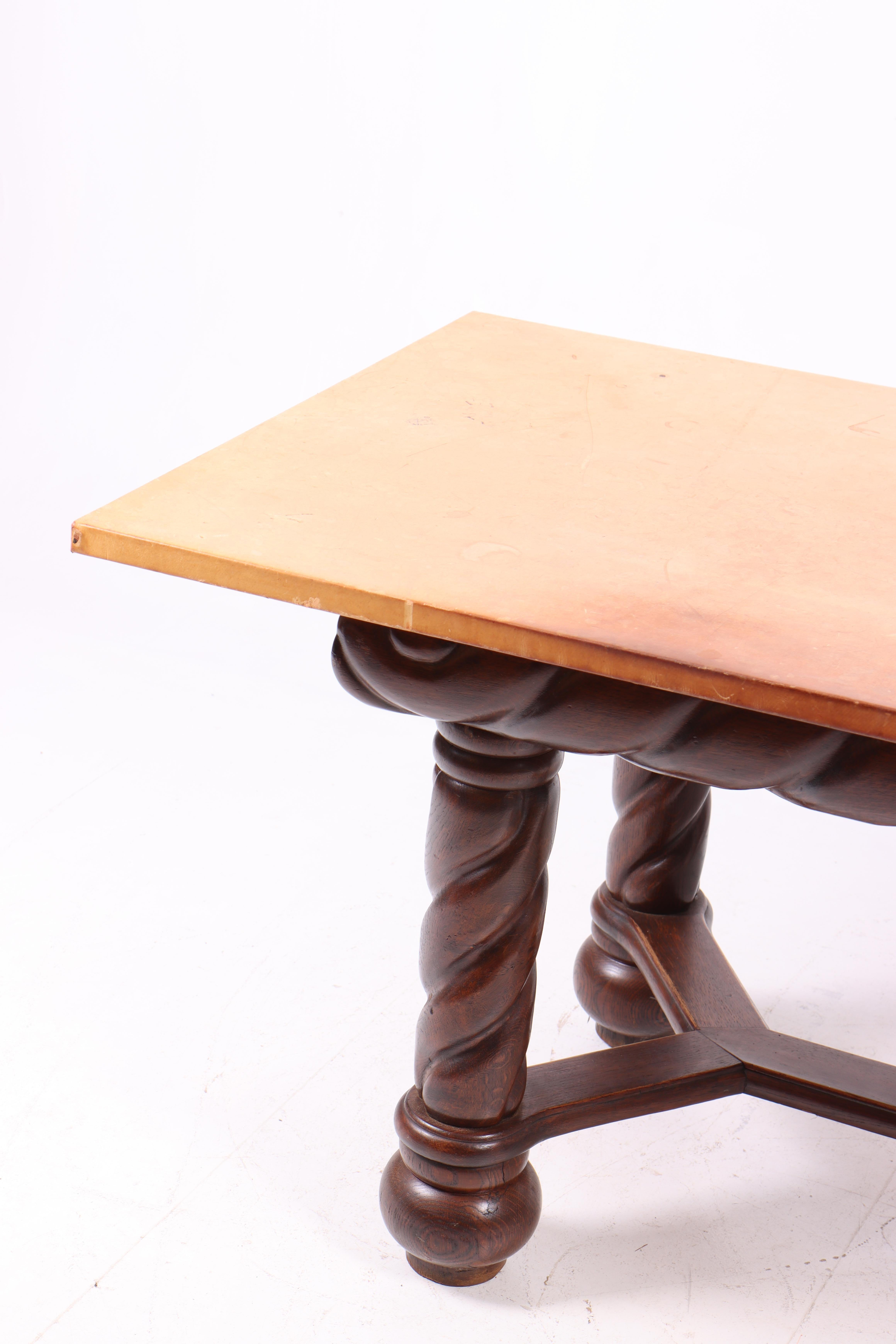 This table is a beautiful example of Danish craftsmanship from the 1940s, created by a Danish cabinetmaker. The frame is made of solid oak, characterized by twisted, sturdy legs that give the table a robust and classic look. The tabletop is newer