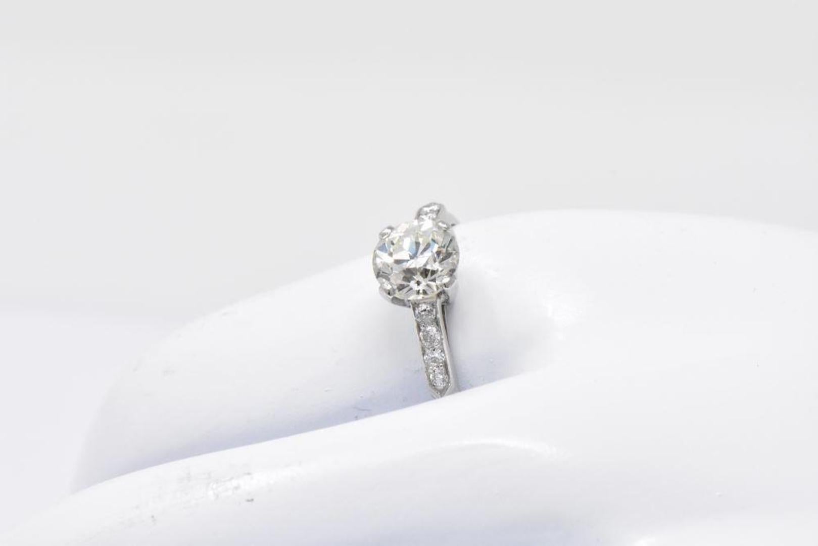 Centering a basket set old European cut diamond weighing 1.37 carats, L color with SI1 clarity

Flanked by round brilliant cut diamonds, bead set in a pointed shoulder motif, weighing approximately 0.12 carat total; eye-clean and white

Completed by