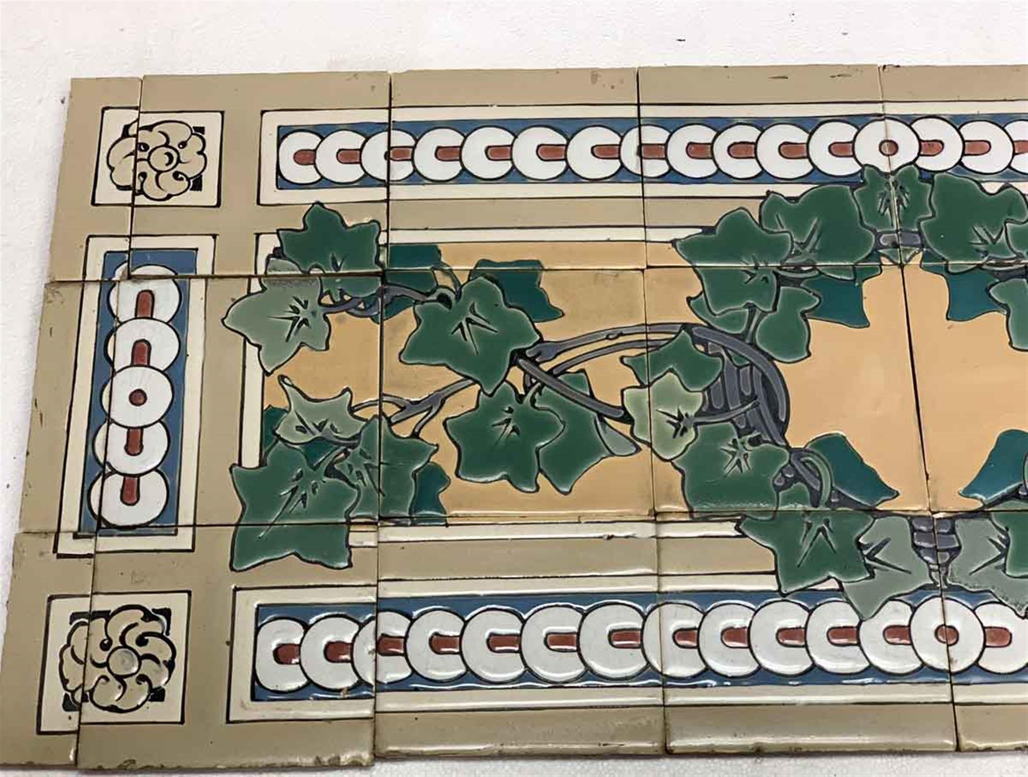 Tan ceramic floor tile set with a green leafy design and blue, white, red and gray decorative details from the 1940s. The tile surface is slightly crackled. There are imperfections and minor chips & scrapes from age. Priced as a set. The set