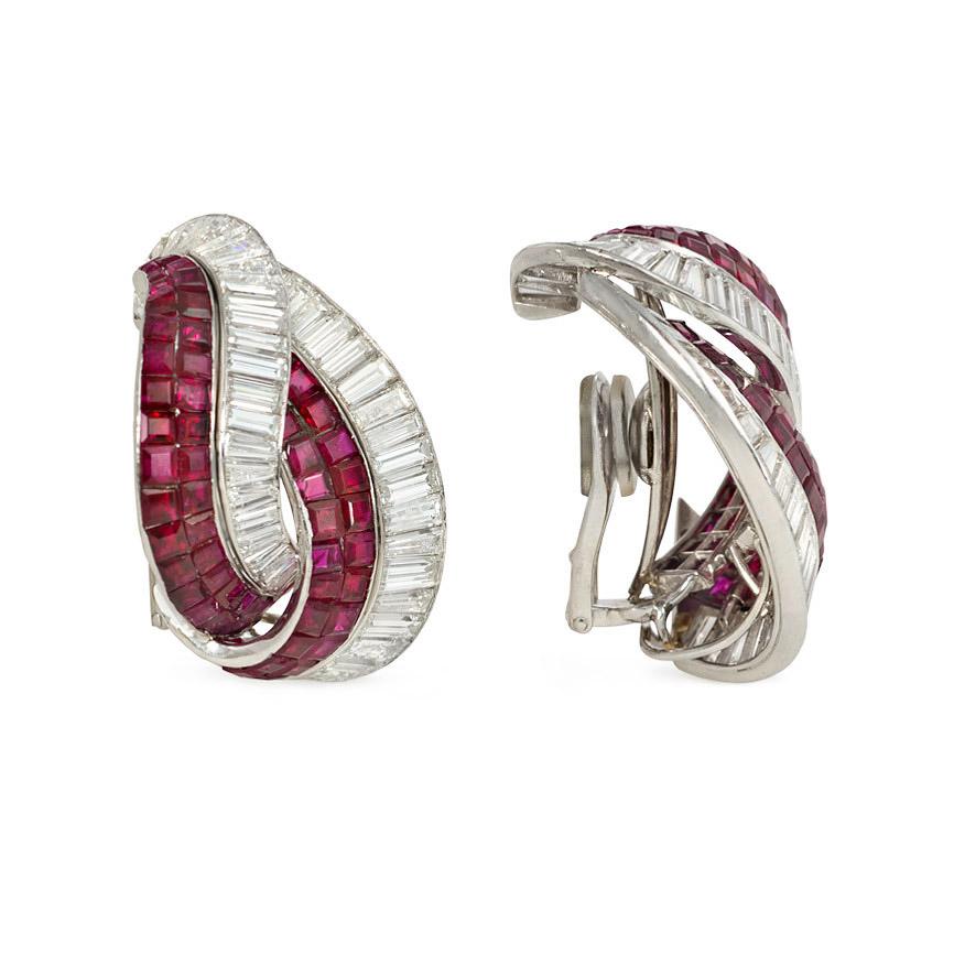 Paire de boucles d'oreilles rétro en diamant baguette et rubis de Birmanie sertis de manière invisible, avec des motifs tourbillonnaires se chevauchant, en platine avec des dos de clip. 11,50 ct. de diamants, 14,00 ct. de rubis.