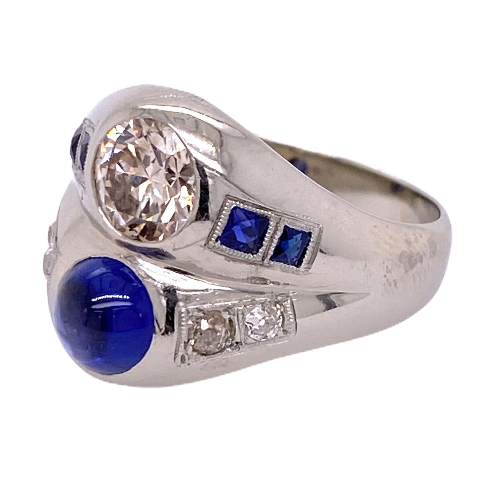 Beautiful diamond and blue sapphire estate ring fashioned in 18 karat white gold. The two stone ring features an approximately 1.20 carat Old European Cut Diamond, cabochon natural blue sapphire, and side diamonds (.25 ctw). The diamonds are graded